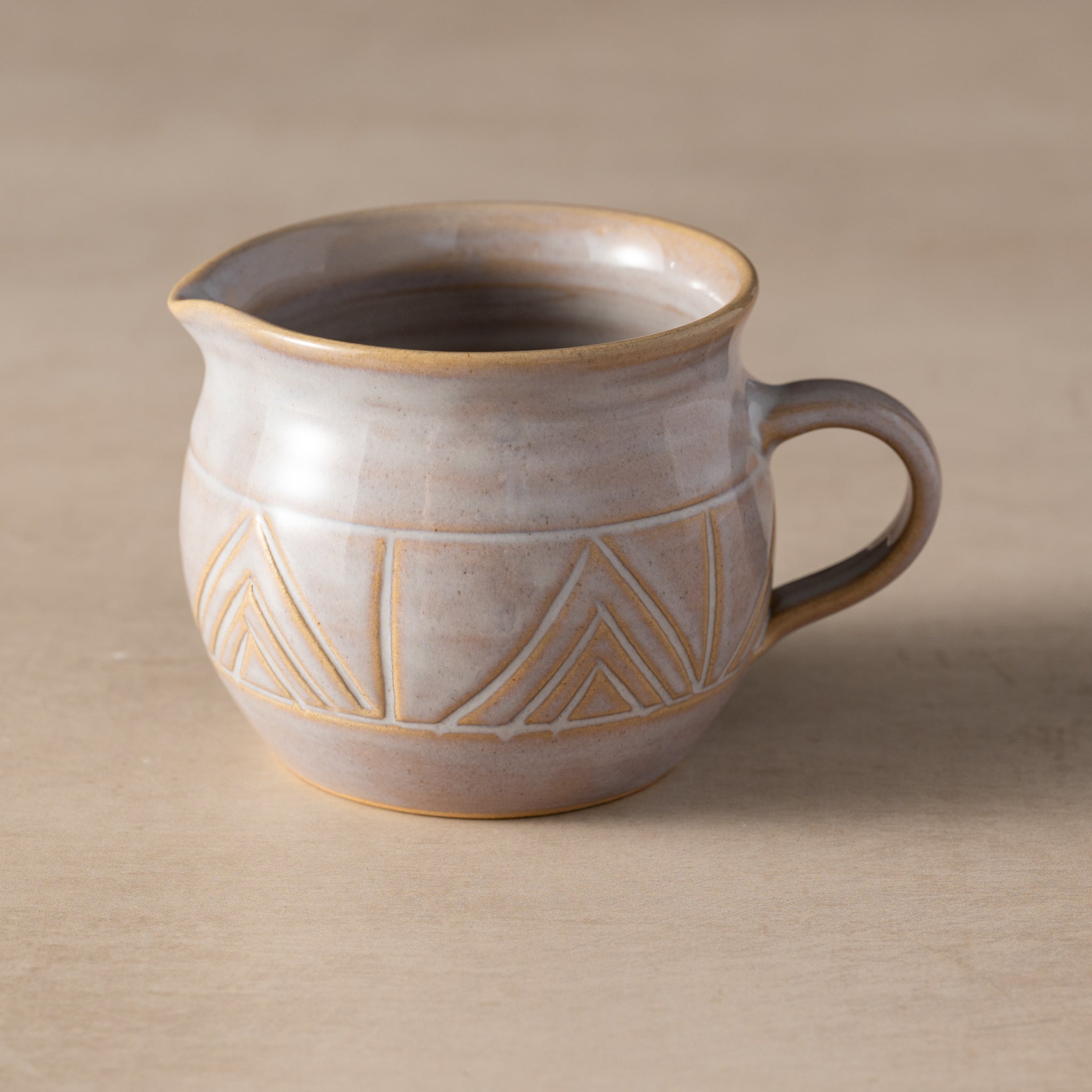 Ceramic pitcher with geometric patterns on a beige background