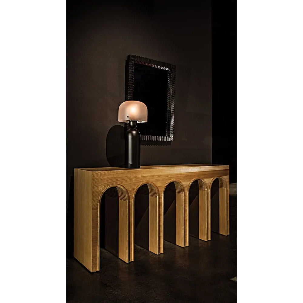 Wooden console table with a lamp against a dark wall