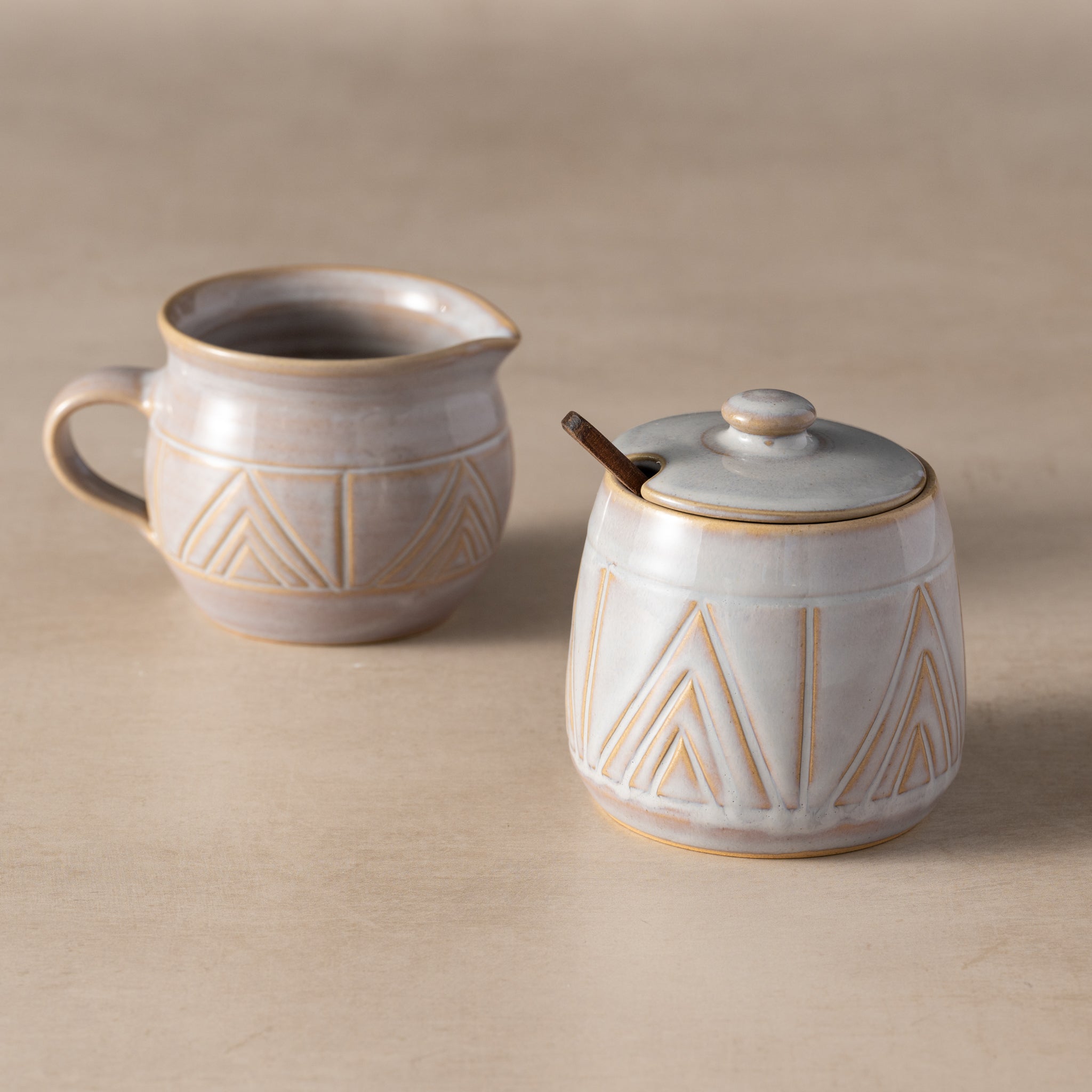 Two ceramic containers with geometric patterns on a beige background