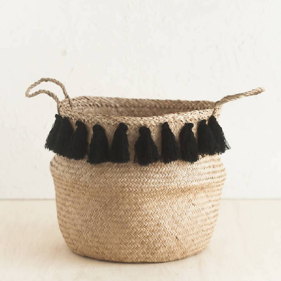 Woven basket with black tassels on a light background