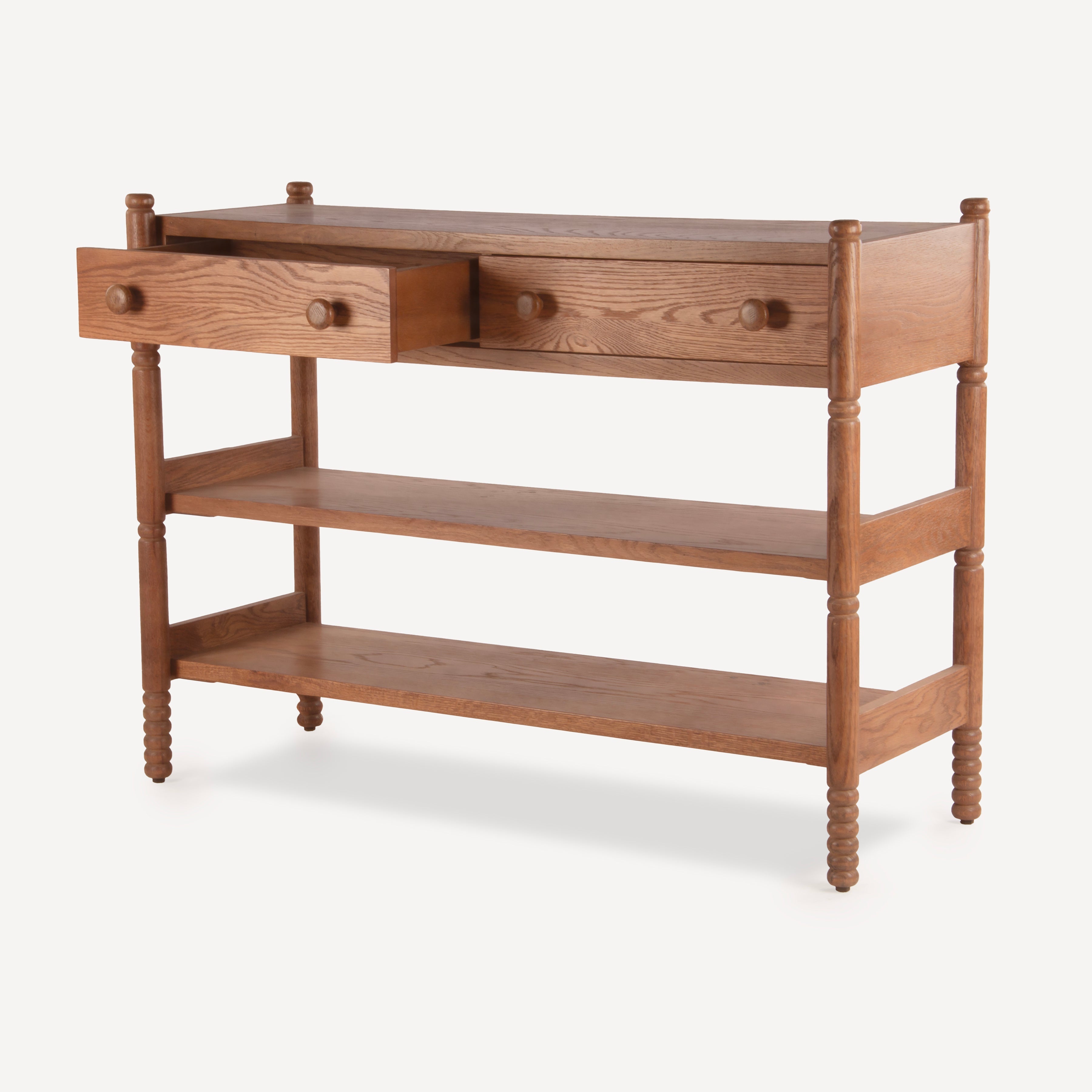 A mid-century modern wooden console table with a warm medium-brown finish, featuring two drawers on the top shelf, a central open space, and two lower open shelves. The table has turned spindle legs and round wooden knobs.