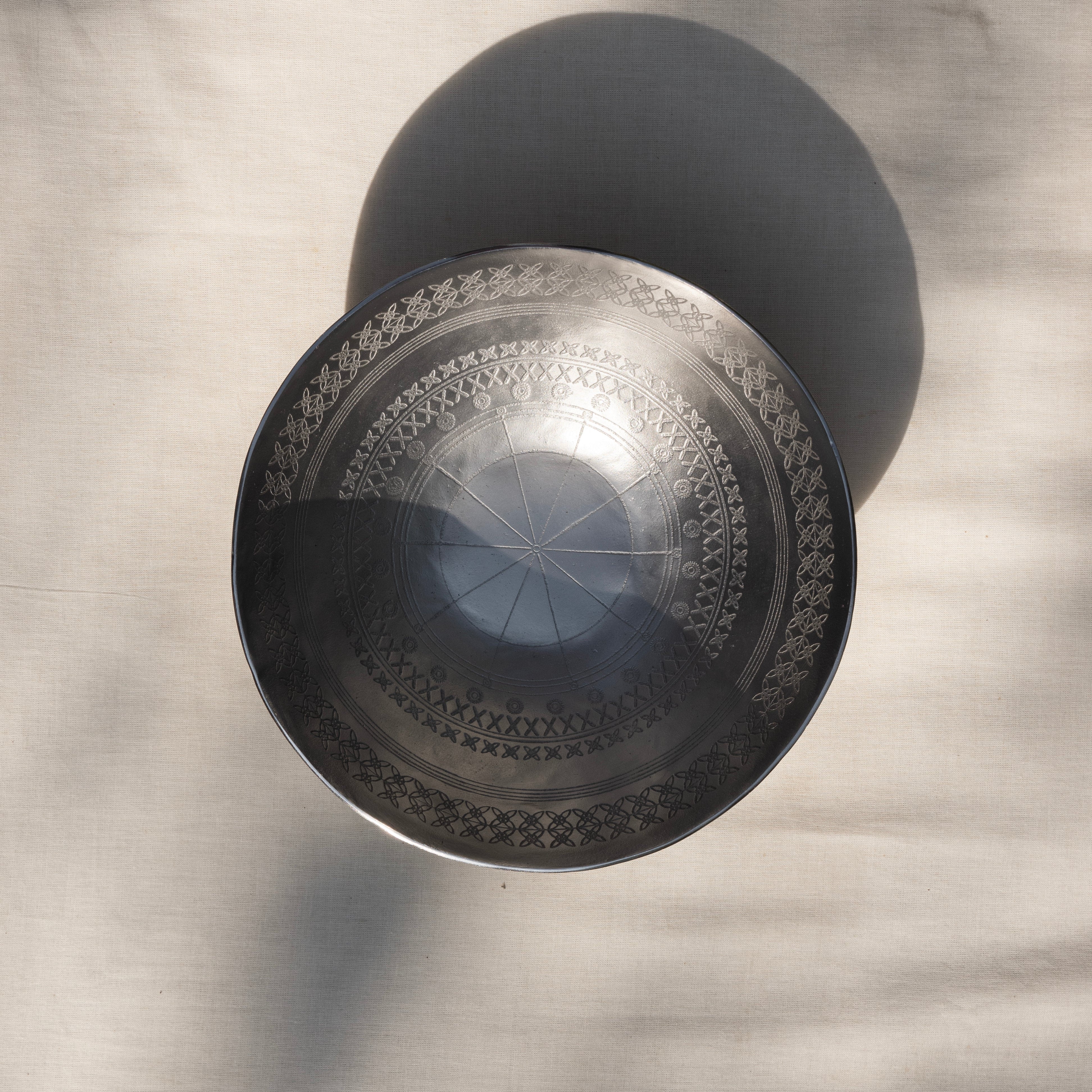 Metallic bowl with mandala design on a textured gray background