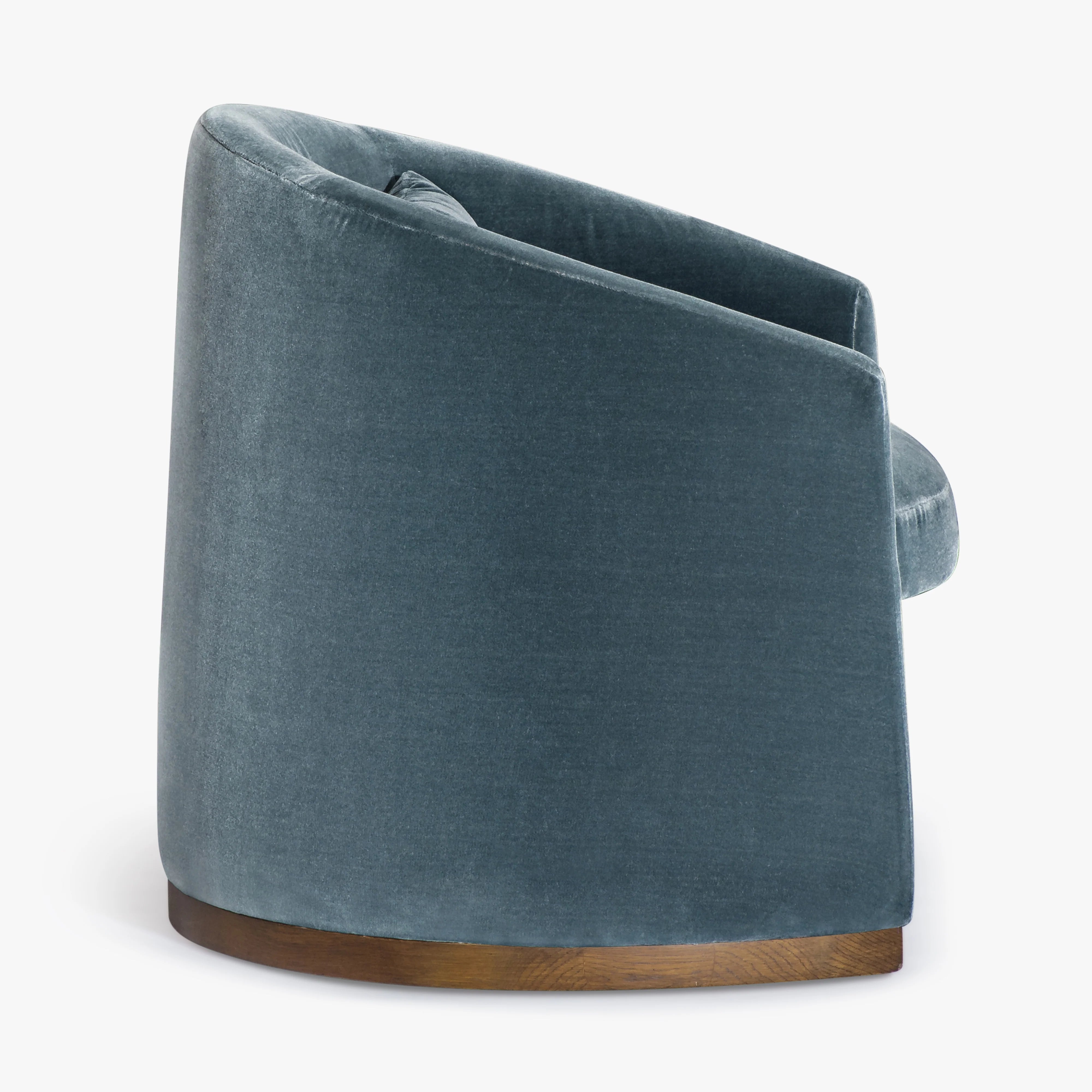 A modern barrel-style armchair upholstered in textured blue-gray velvet with a curved wooden base, shown from a three-quarters angle against a plain white background.