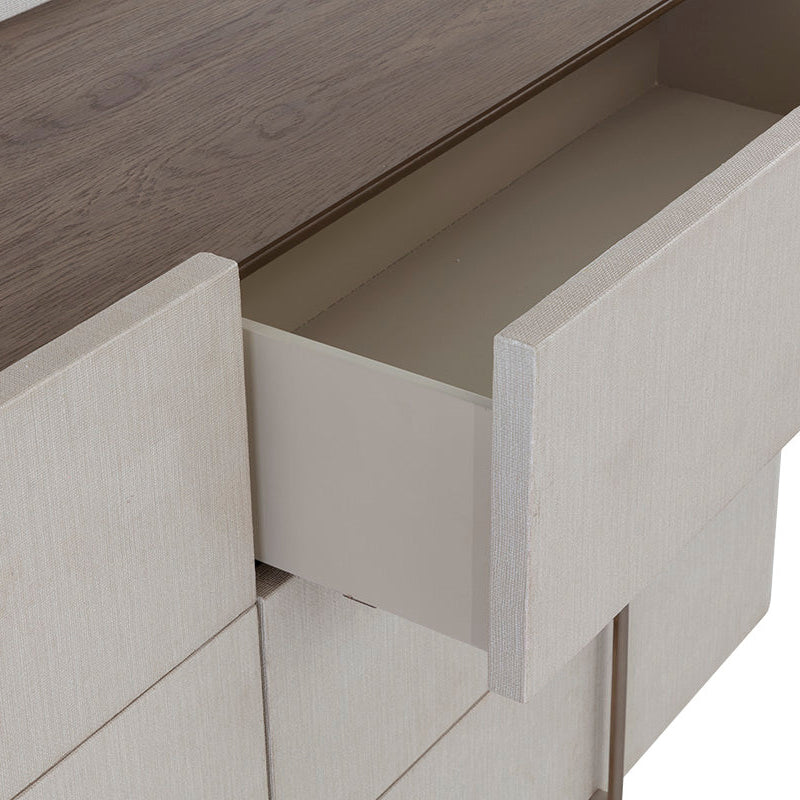 Close-up of a modern dresser or cabinet with a dark wood top and light beige textured drawer fronts, with one drawer pulled open.