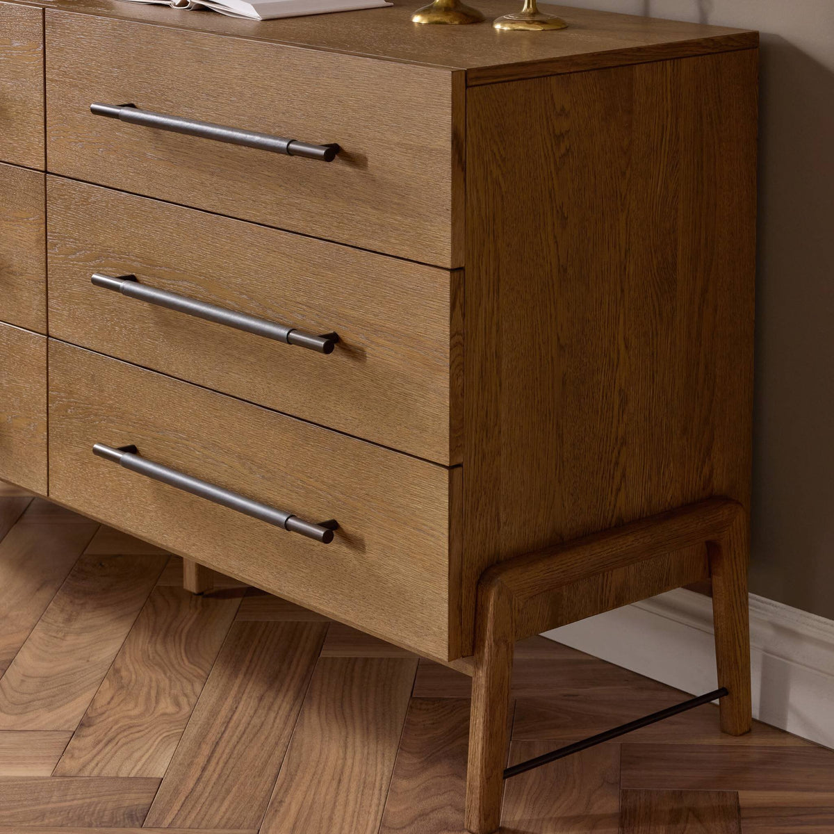Wooden dresser with three drawers on a wooden floor.