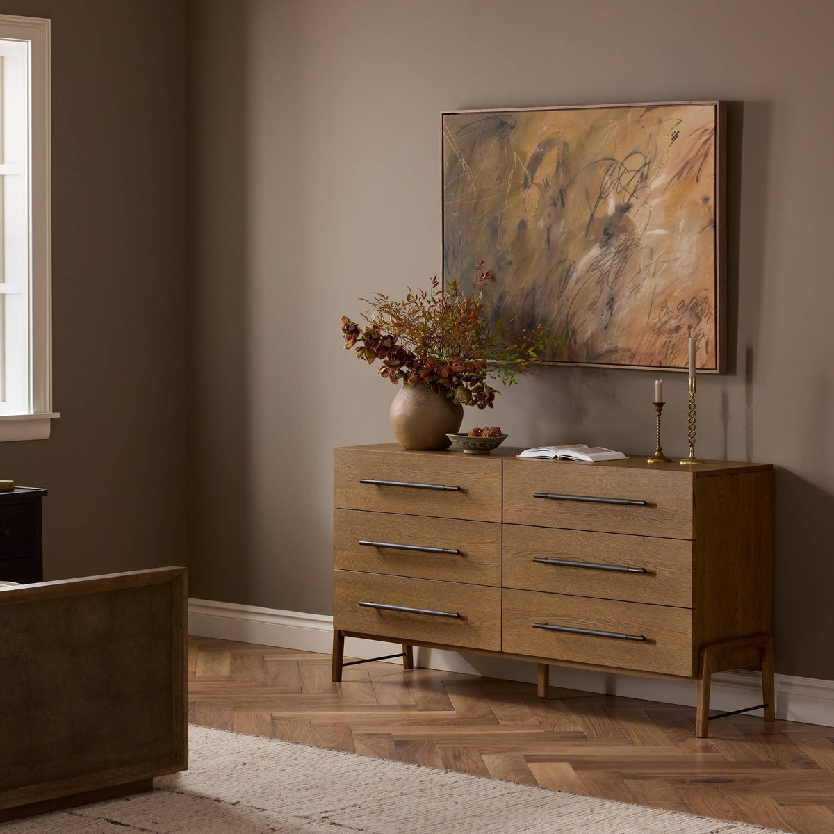 Wooden dresser with decorative items in a room with a painting on the wall.