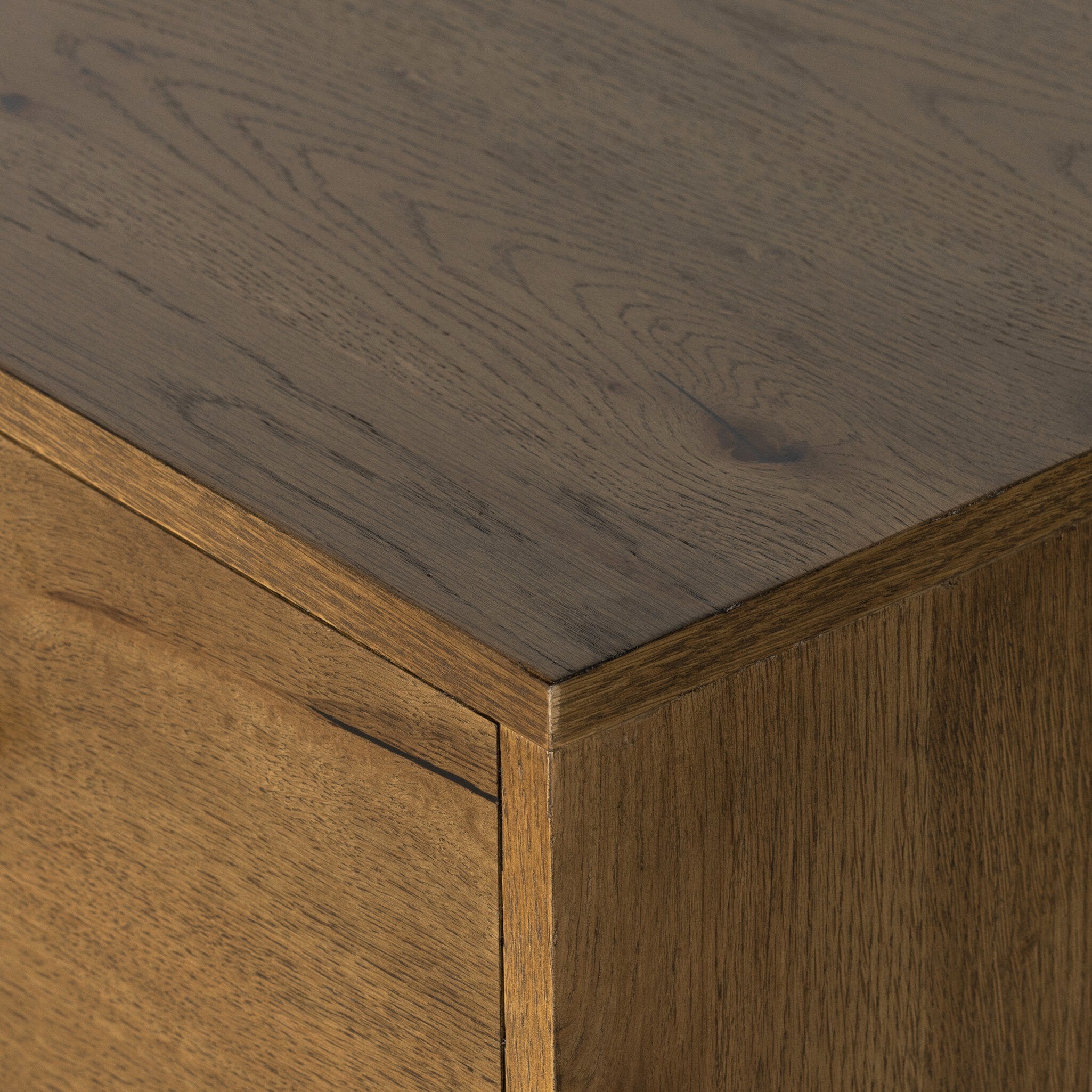 Close-up of a wooden cabinet corner with a dark brown countertop.