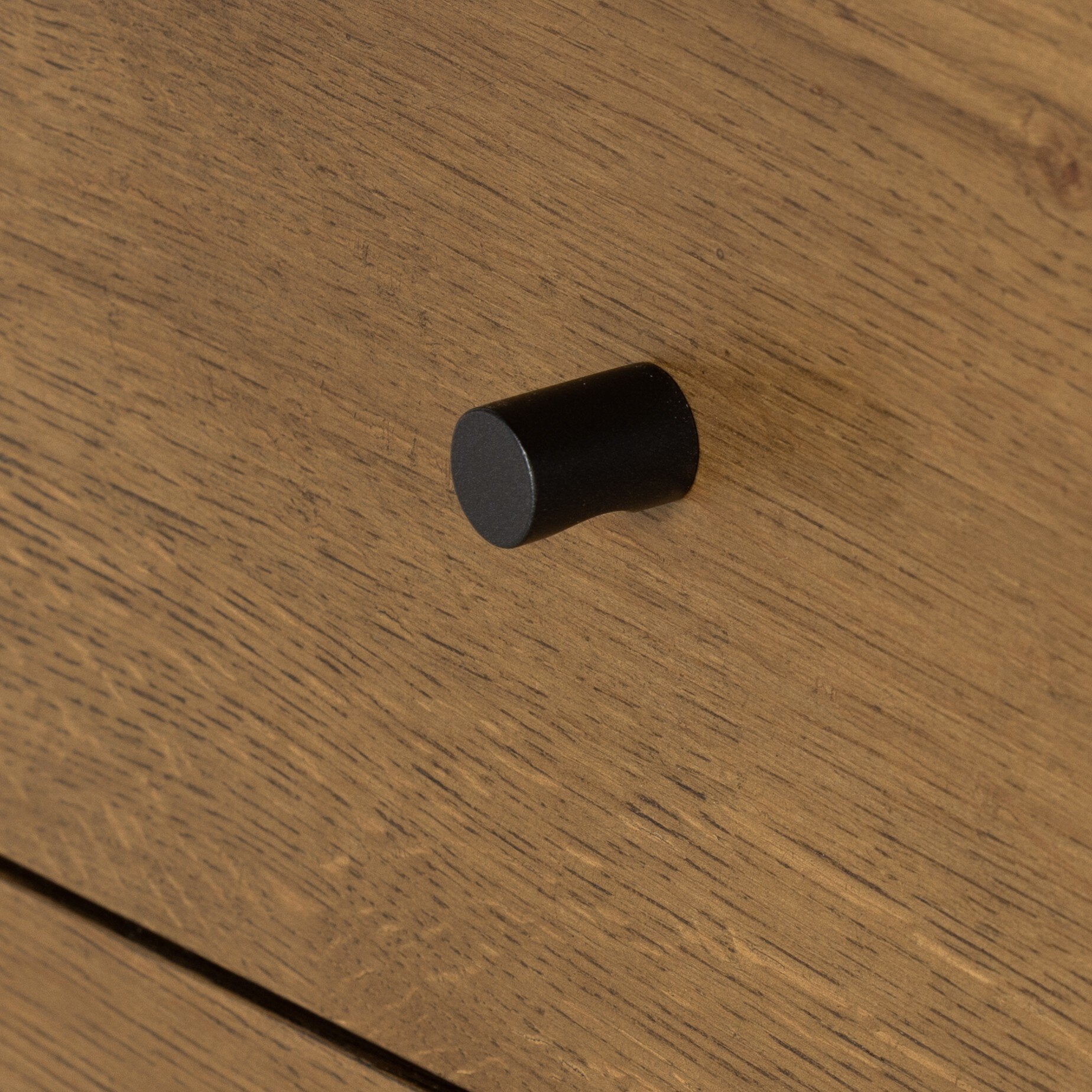 Black cylindrical knob on a wooden surface