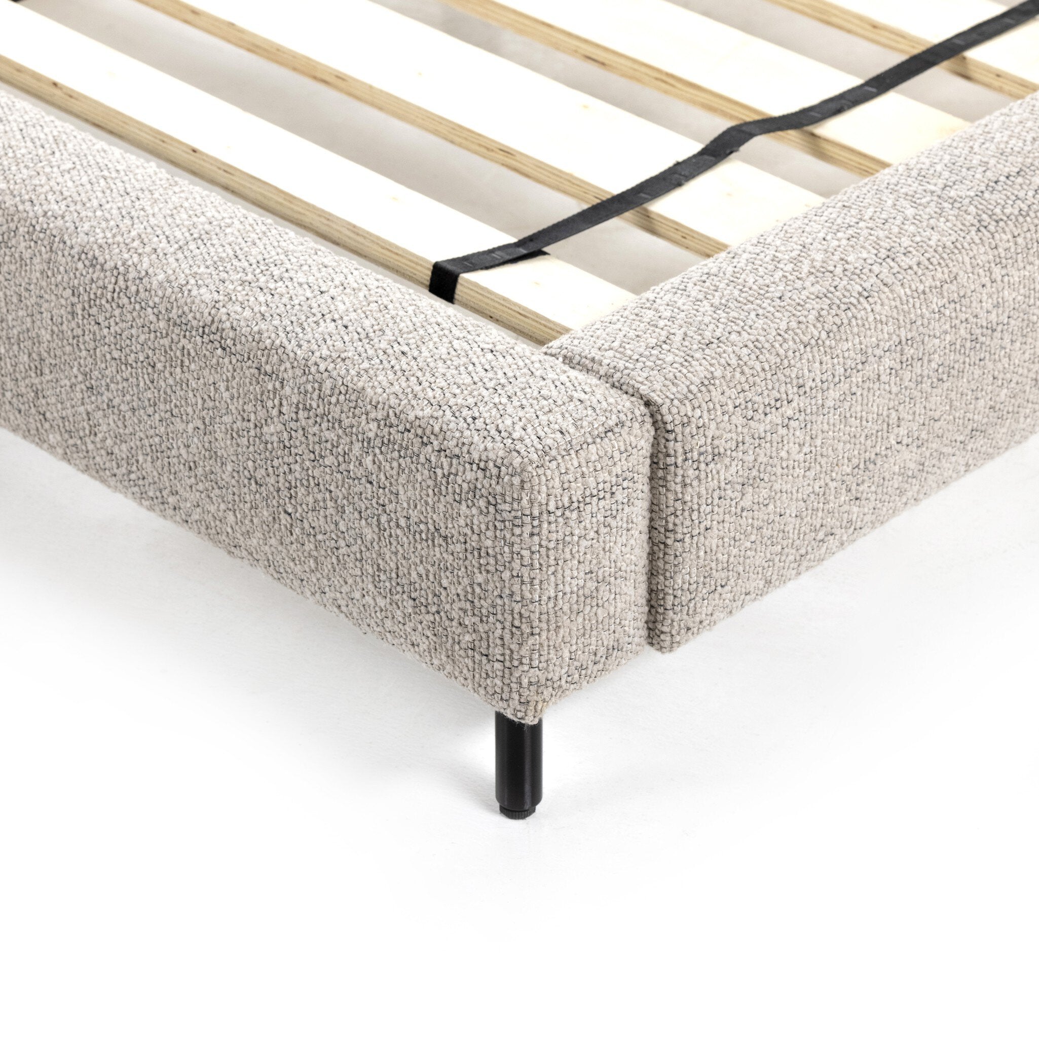 Beige upholstered bed frame with wooden slats on a white background