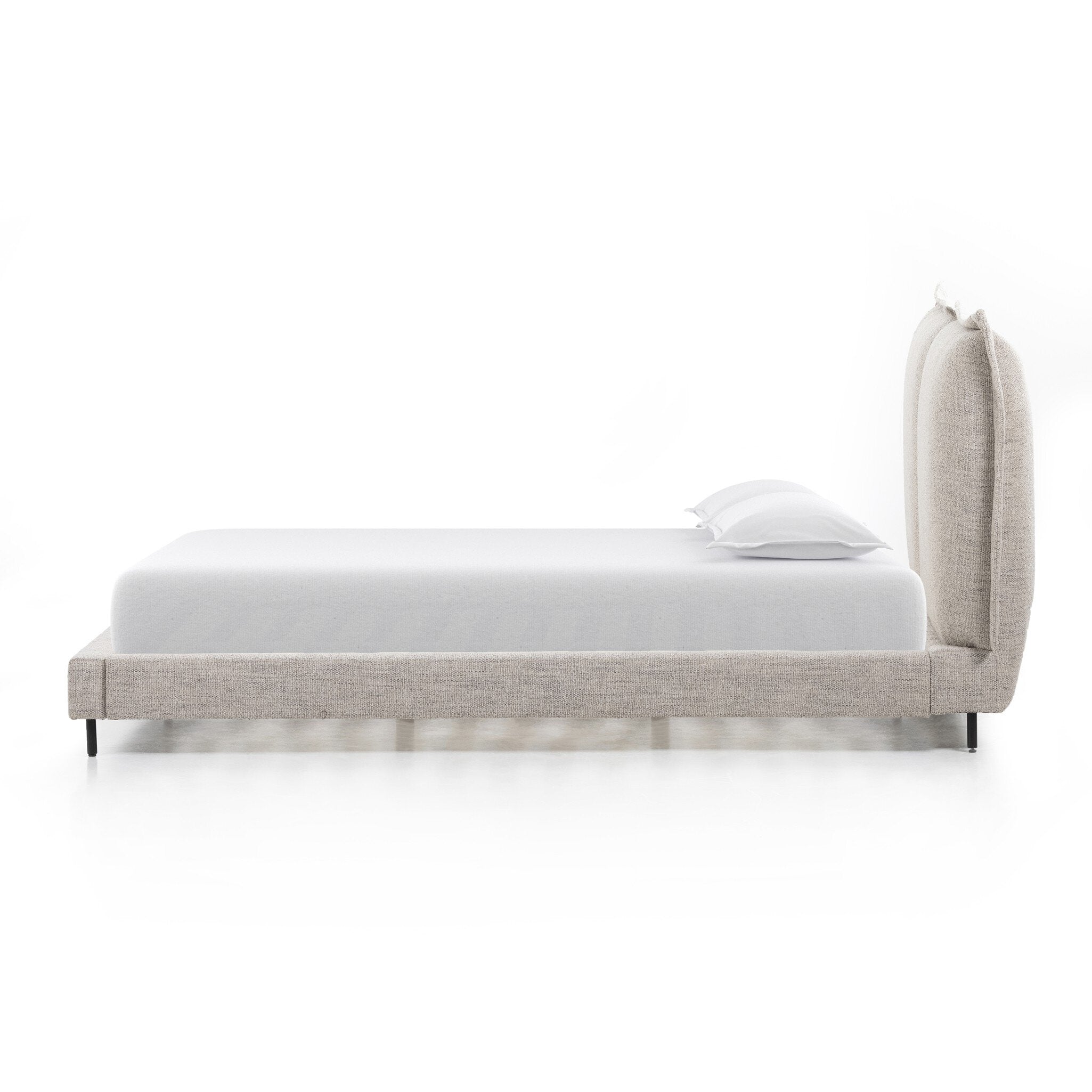Beige upholstered bed with white bedding on a white background