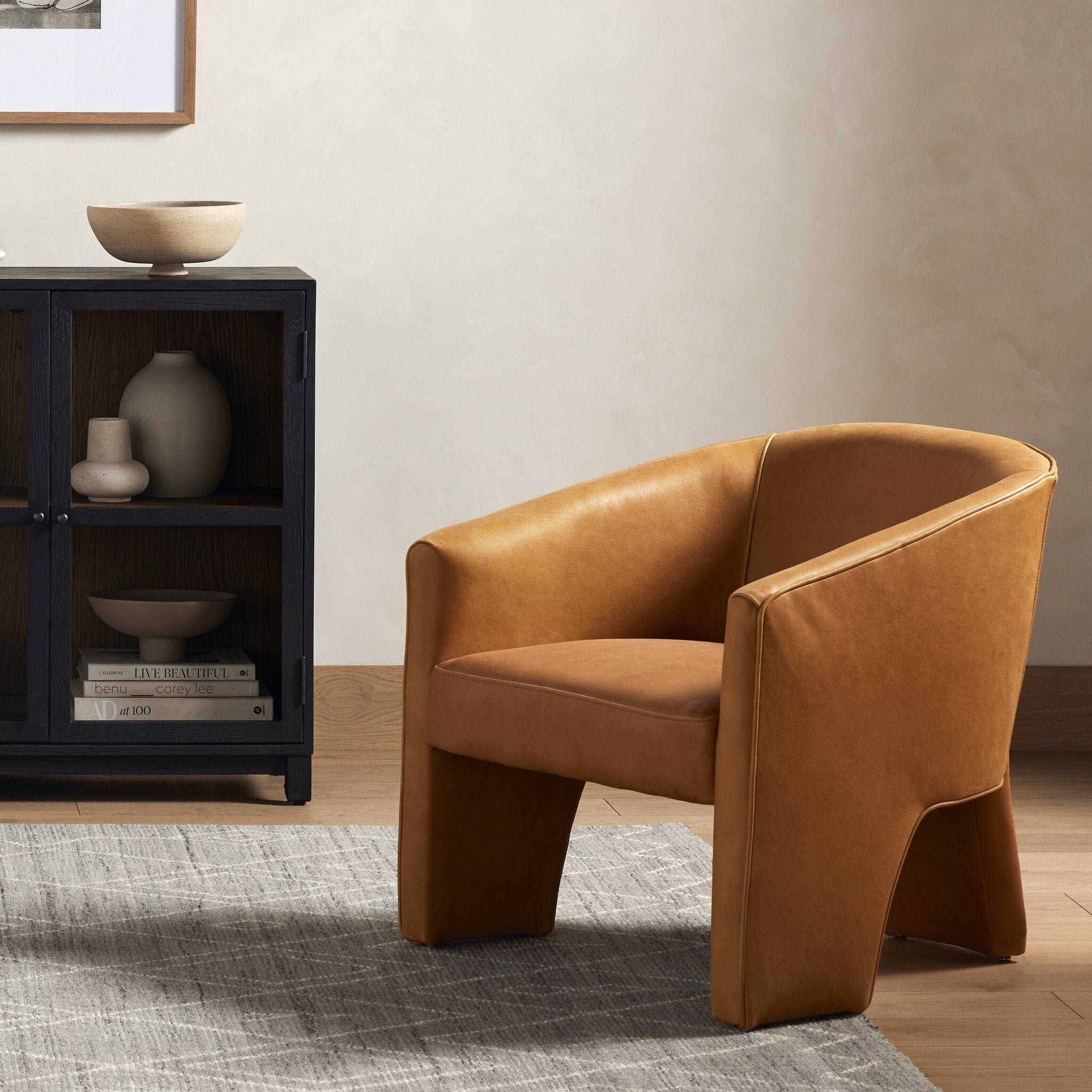 Brown leather armchair in a room with a black cabinet and decorative items.