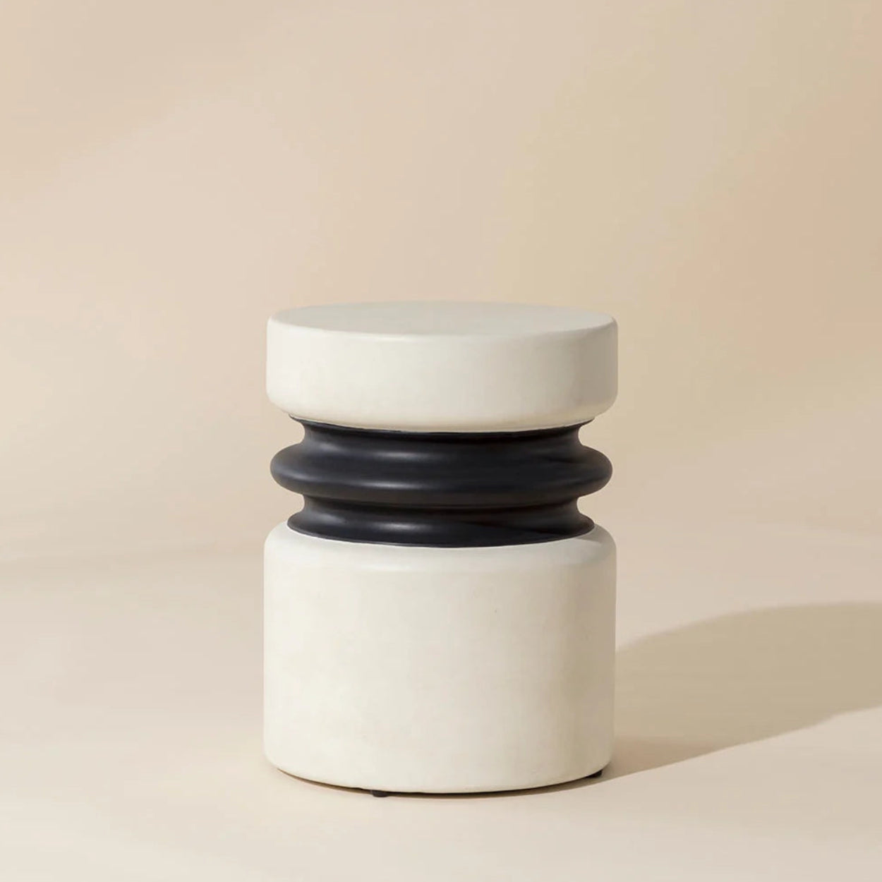 Cylindrical outdoor end table with black accent on a beige background