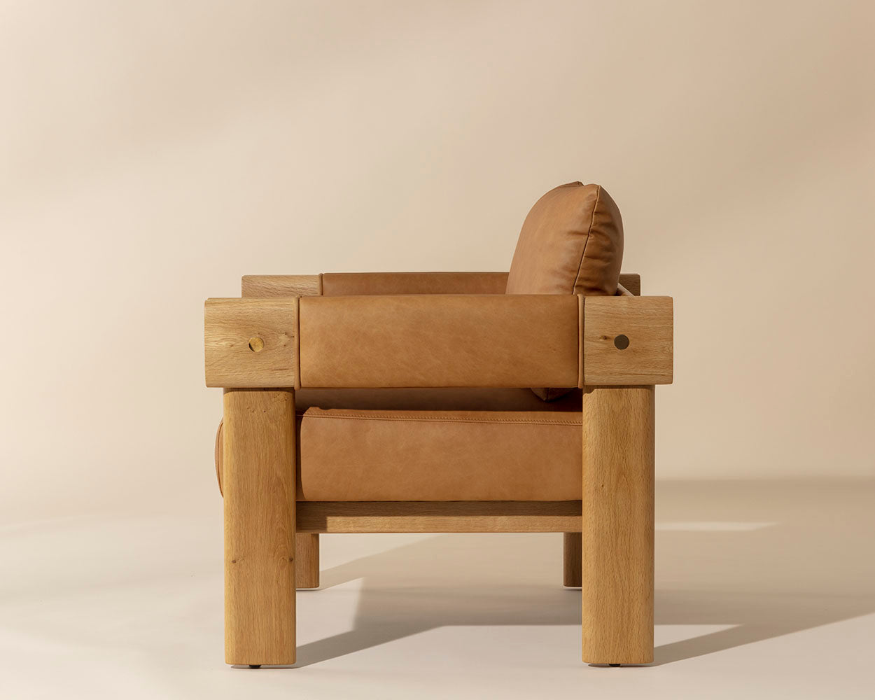 Brown leather armchair with wooden frame on a beige background