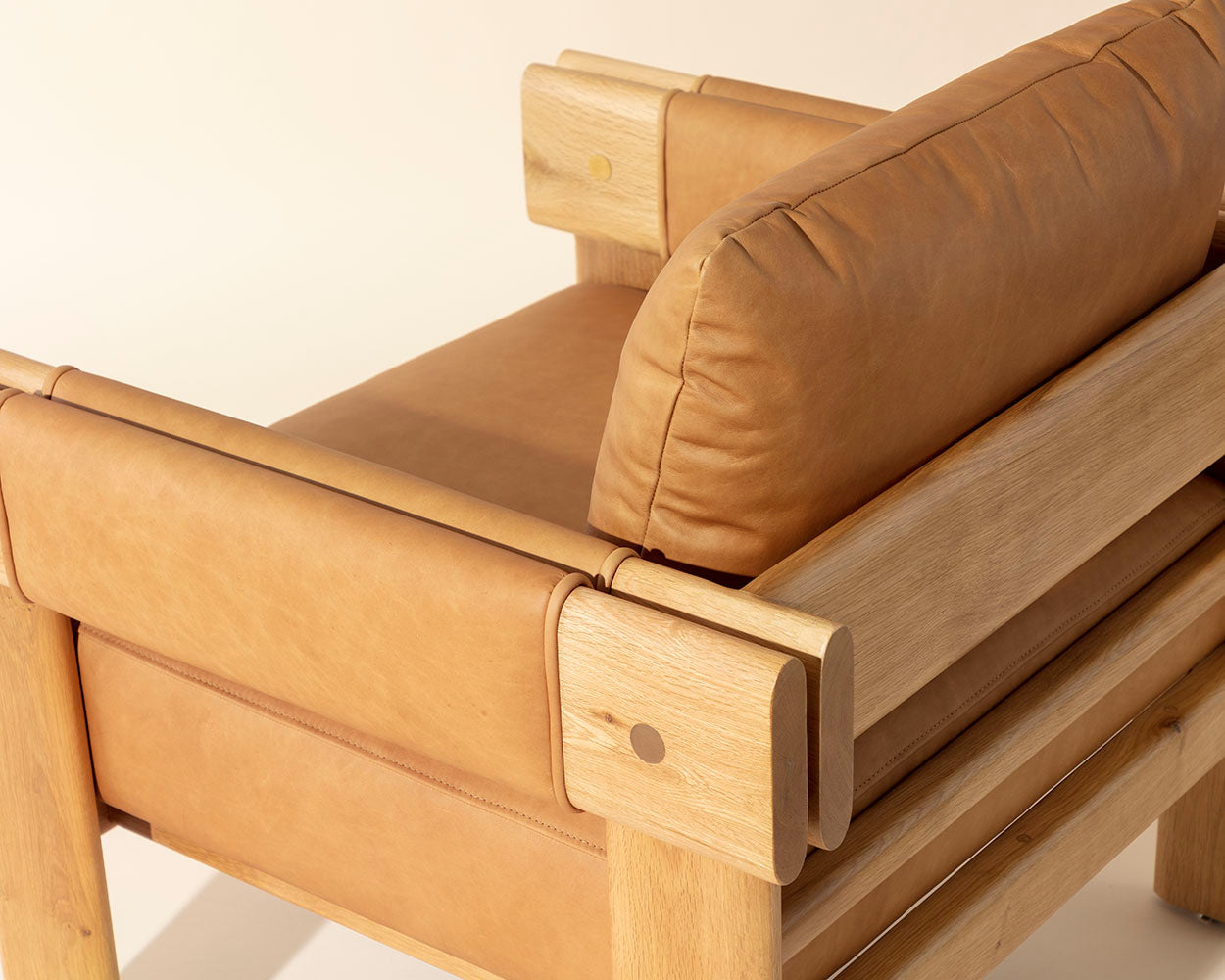 Close-up of a wooden chair with brown cushions on a light background