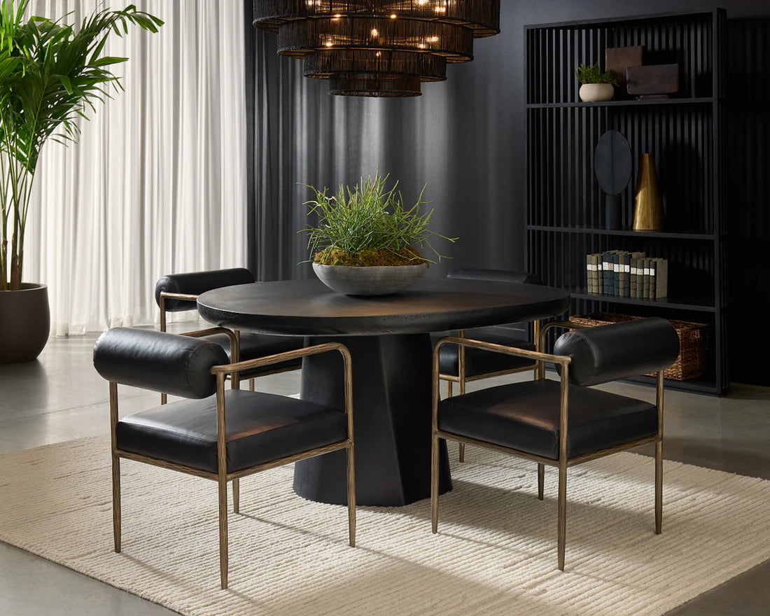 Modern dining room with a round black table and chairs, potted plants, and a bookshelf.