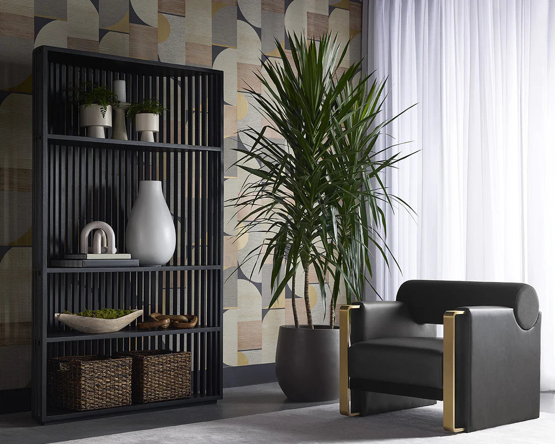 Modern interior with a black bookshelf, black armchair, and a large plant.