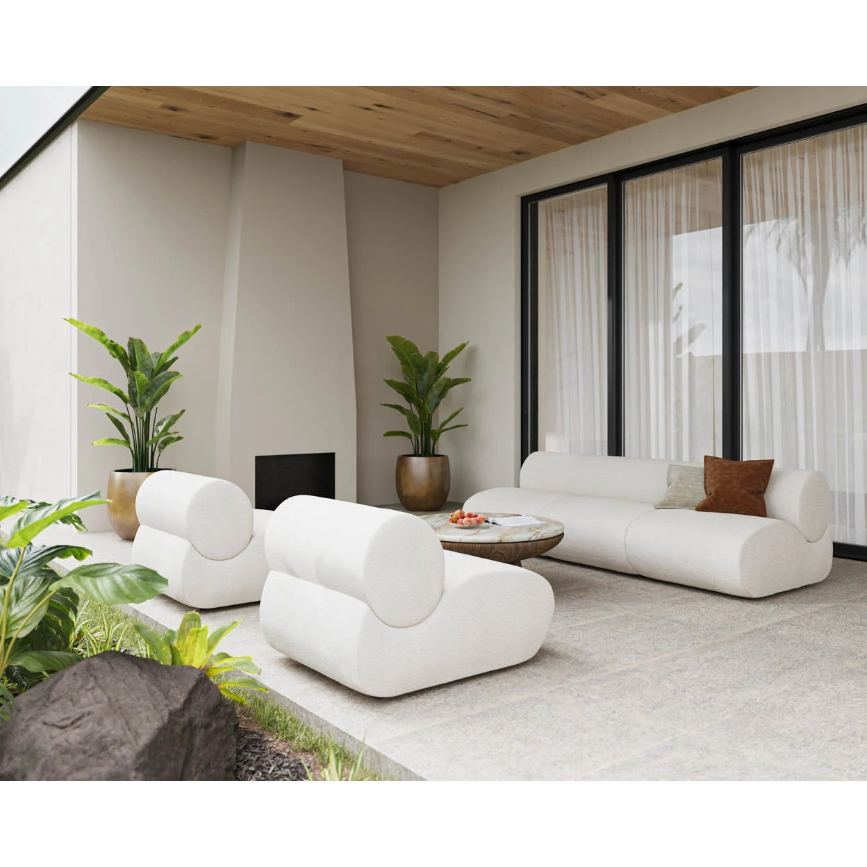 A modern living room featuring a white modular sectional sofa with rounded, cloud-like cushions, paired with a matching armchair, a round coffee table, and indoor plants against a neutral beige wall.