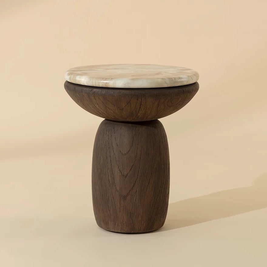 A small wooden stool with a dark brown wood base and a round top featuring a light beige and white marbled pattern, set against a solid warm beige background.