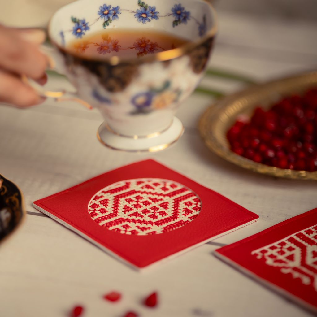 Teacup with floral design on a table with red coaster and berries