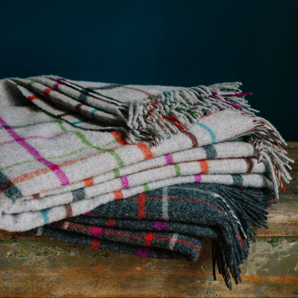 Stack of plaid blankets on a wooden surface with a dark background