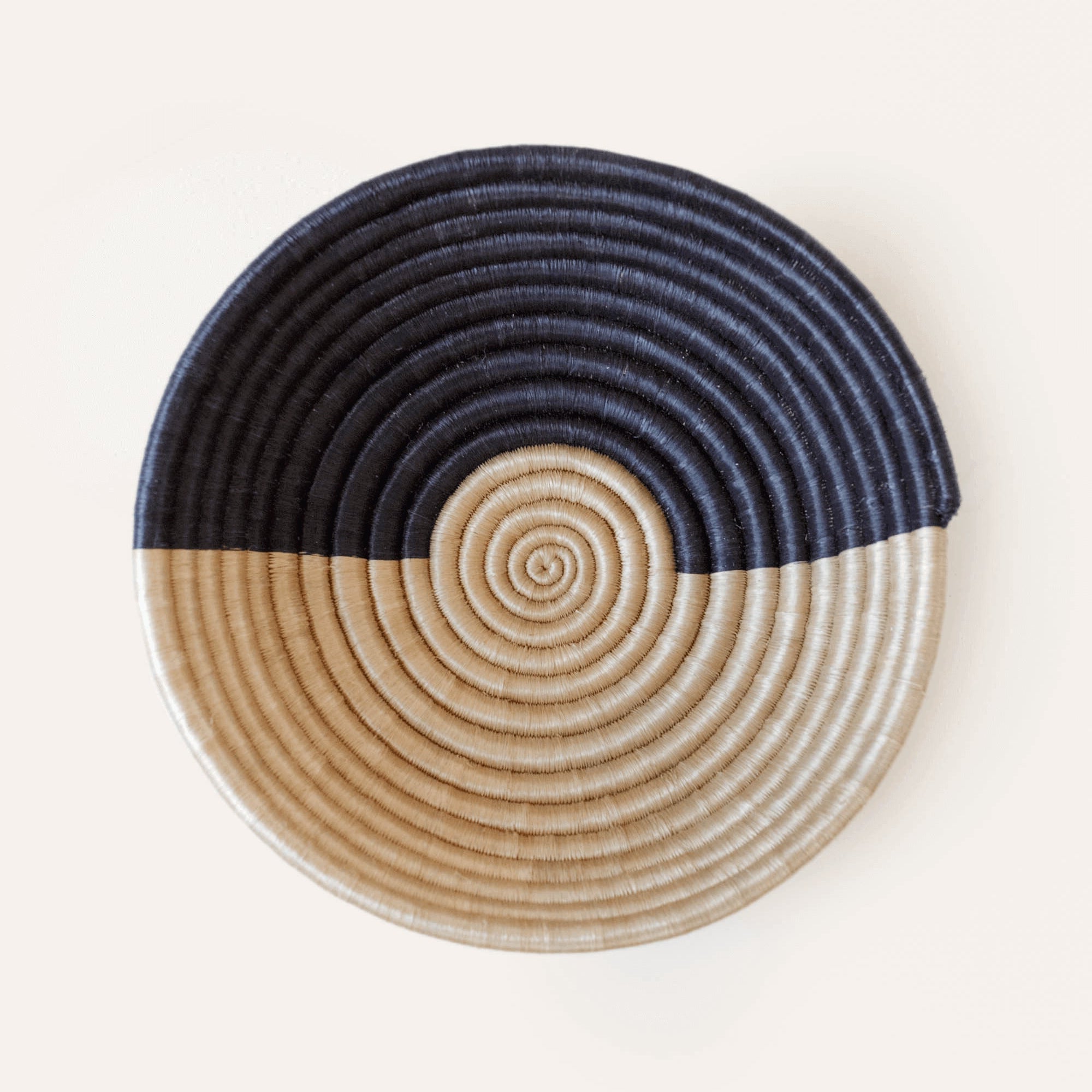 Round woven basket with concentric circle pattern in beige and navy on a white background