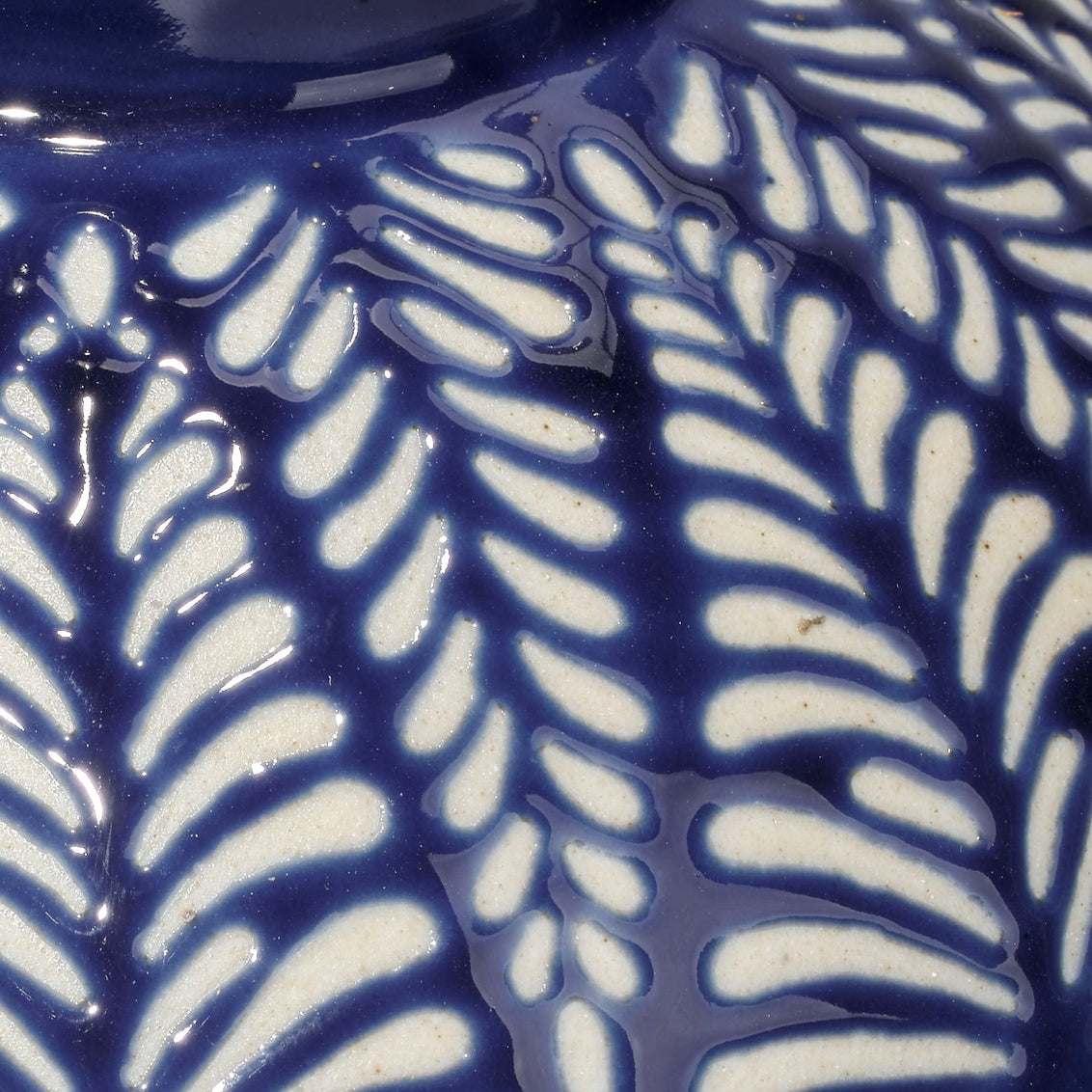 Close-up of a blue ceramic lamp with white leaf pattern