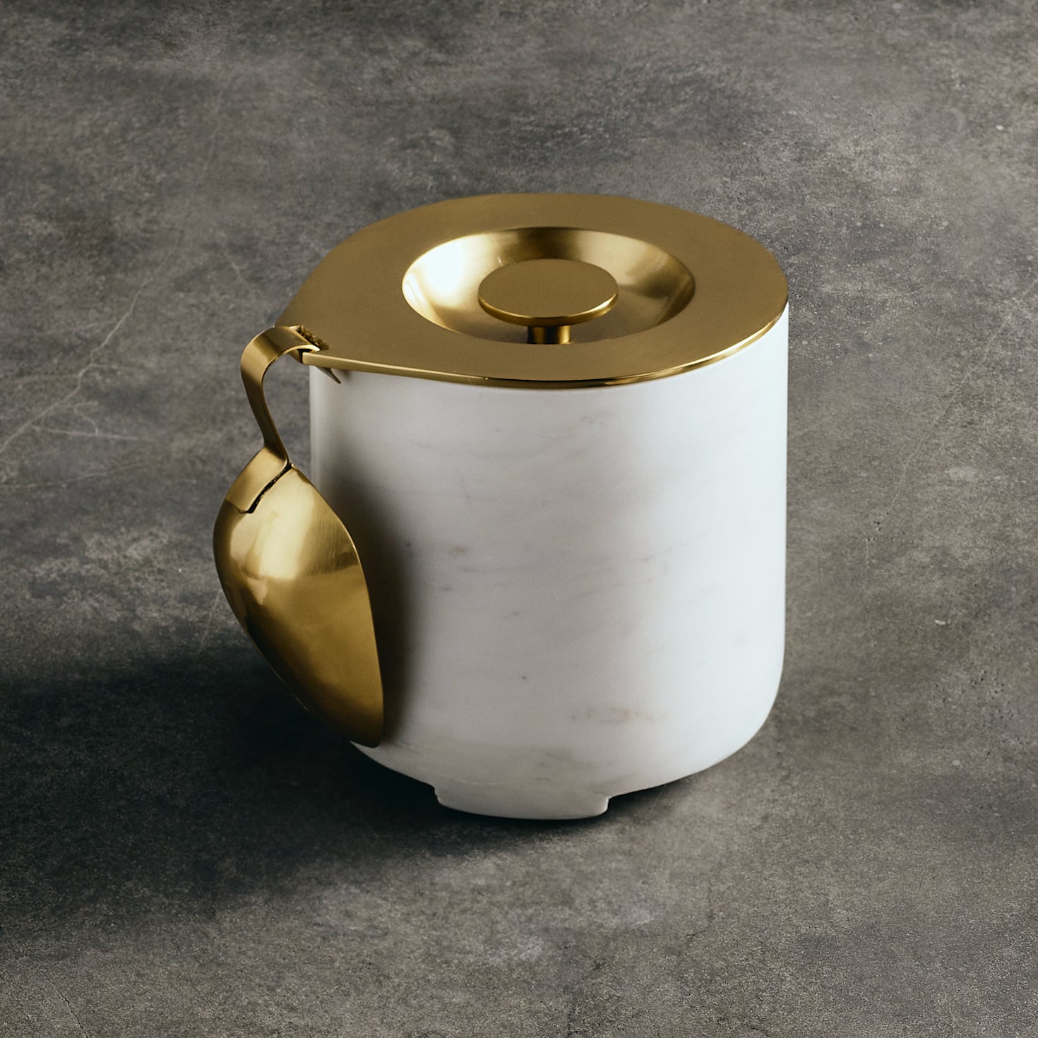 White ceramic ice bucket with gold lid and handle on a gray background