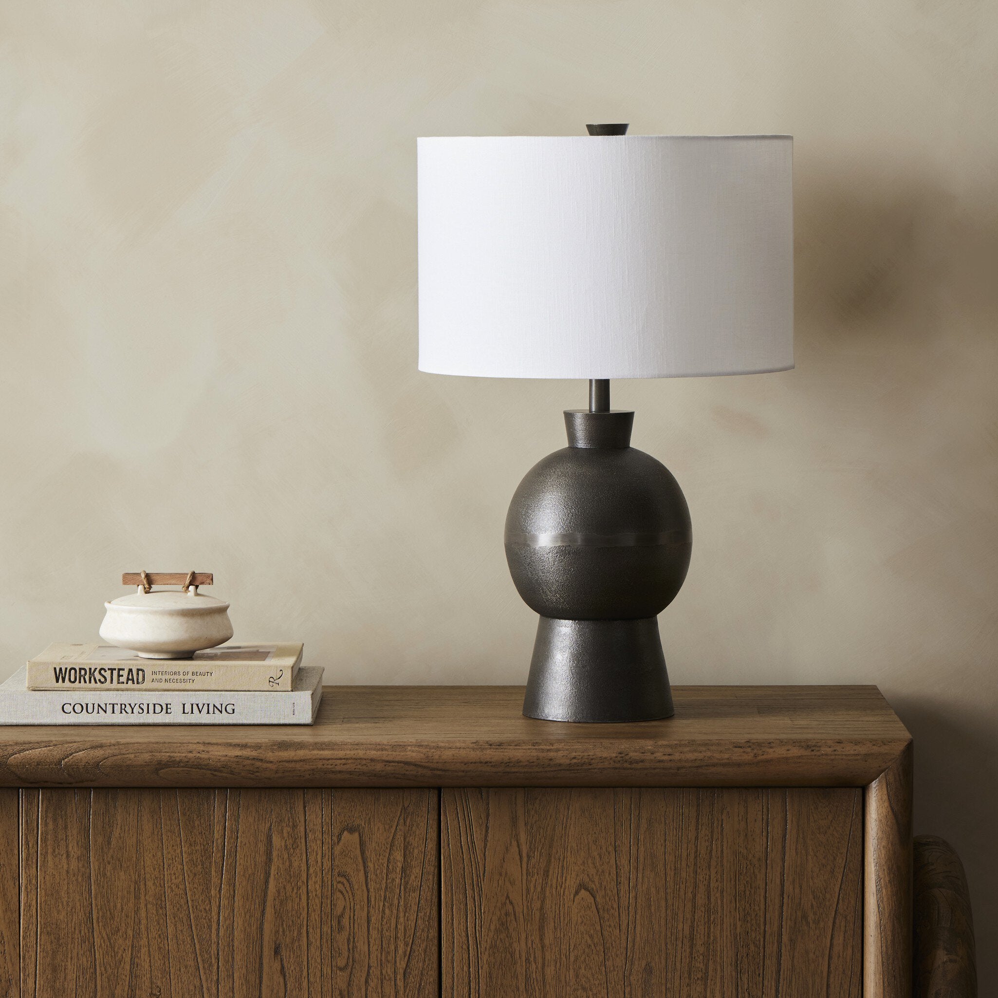 Table lamp with a white shade on a wooden surface against a beige wall