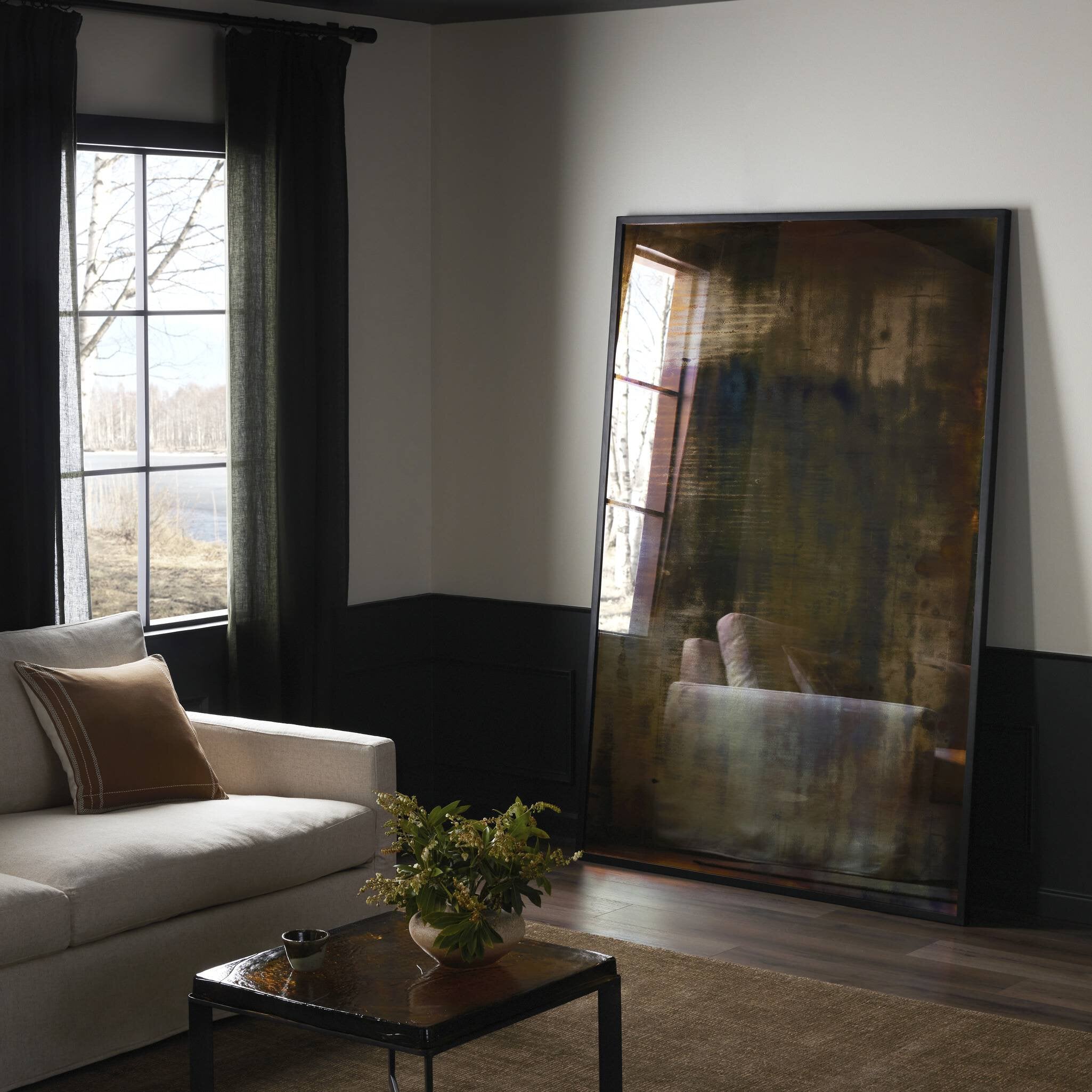 Living room with a large acid-washed floor mirror against the wall, a couch, and a coffee table with a plant.