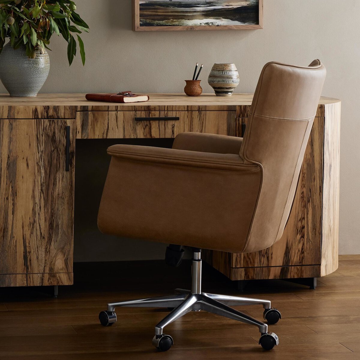 Brown office chair in front of a wooden desk with decorative items.