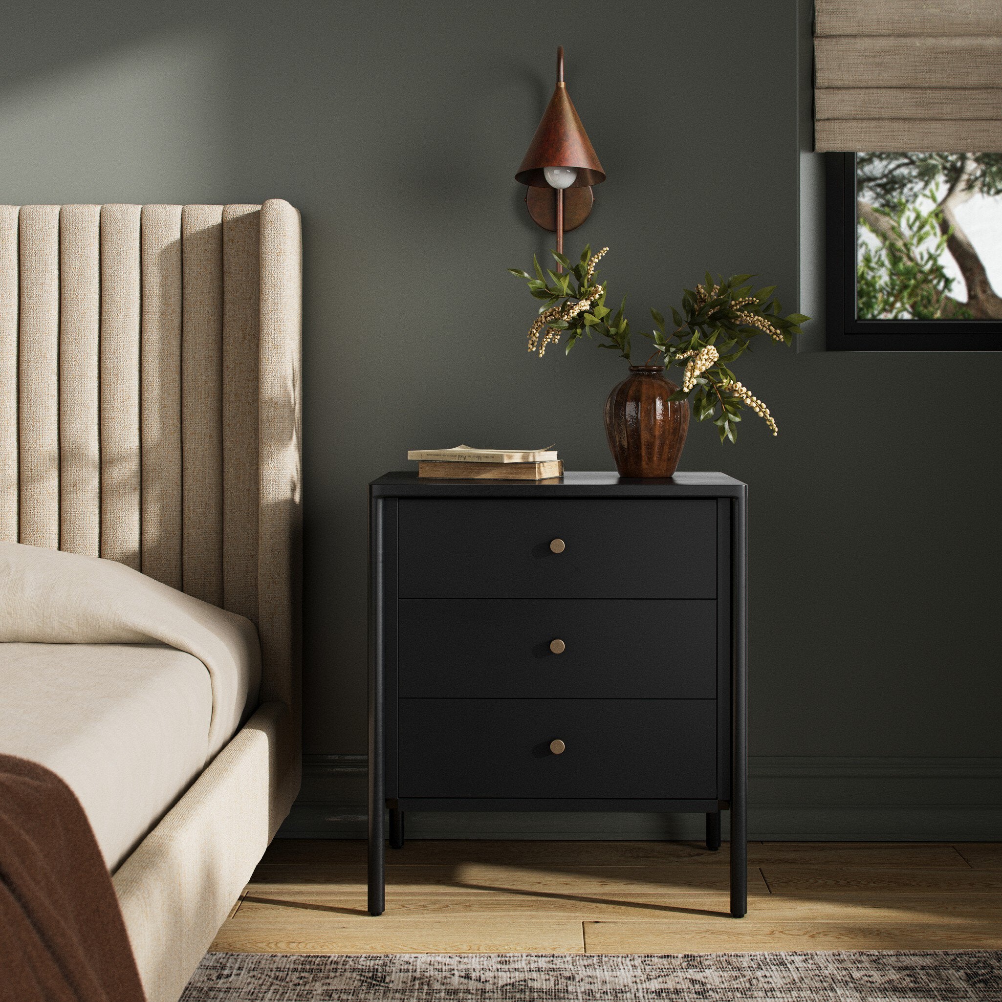 Black nightstand with three drawers next to a beige upholstered bed in a bedroom setting.