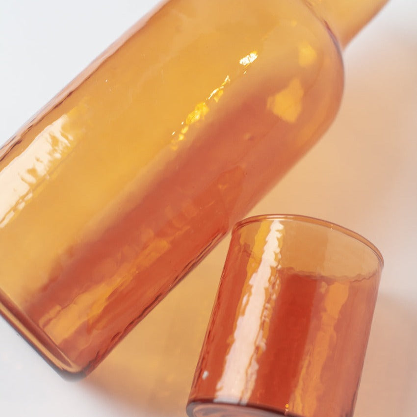 Amber glass bottle and glass on a white background