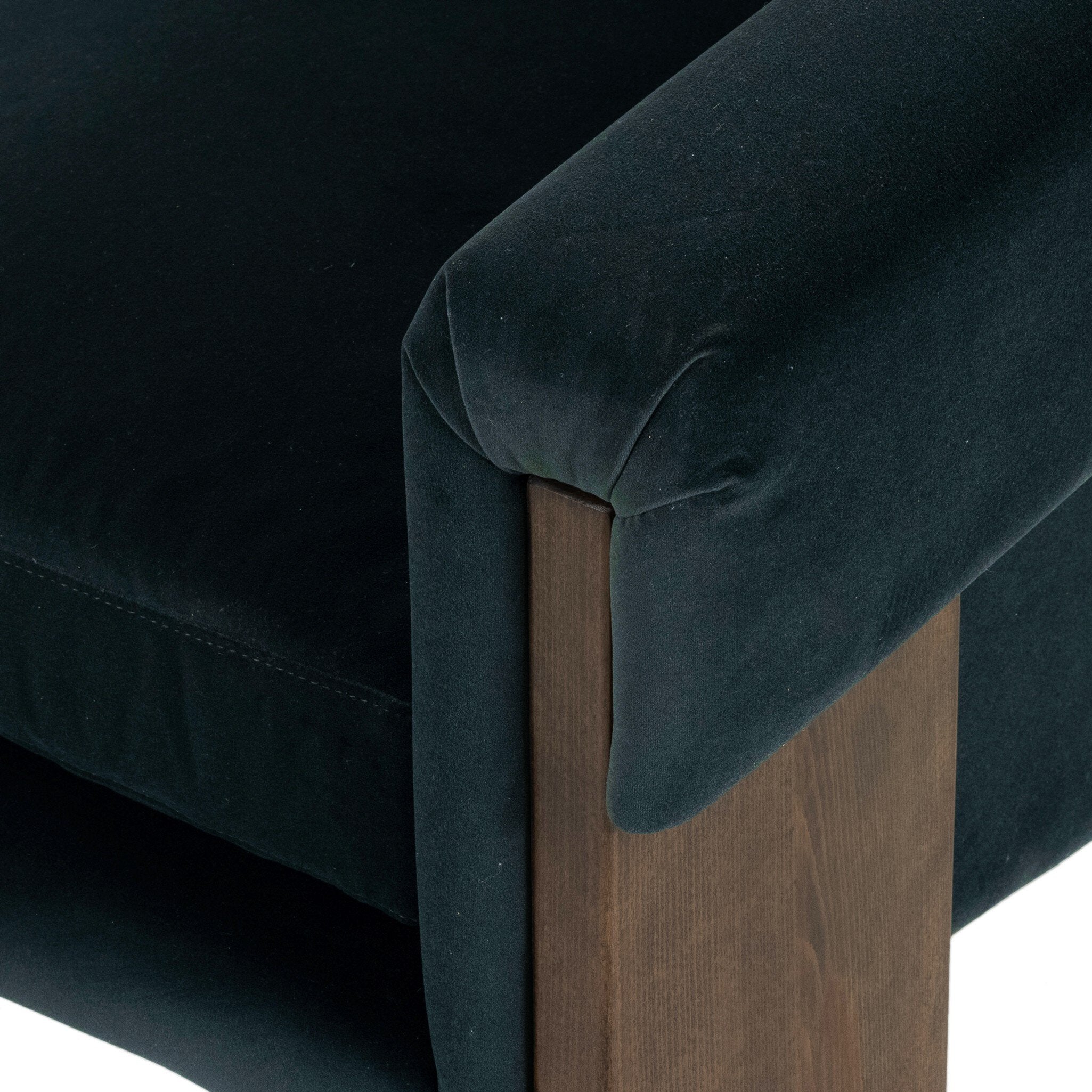 Close-up of a teal velvet chair with wooden legs on a white background