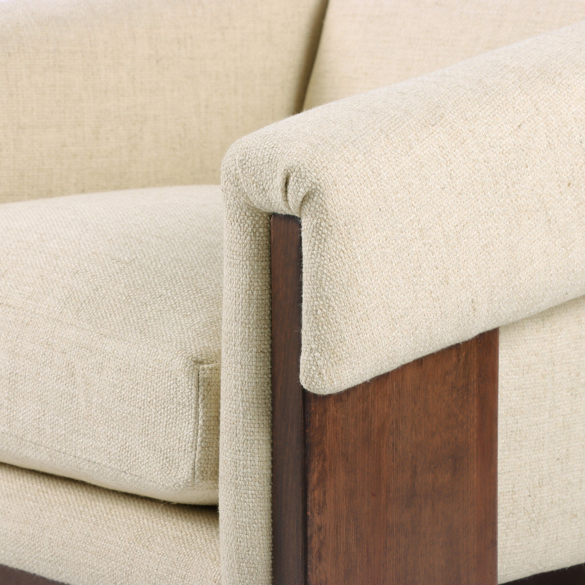 Close-up of a beige upholstered chair with wooden armrests