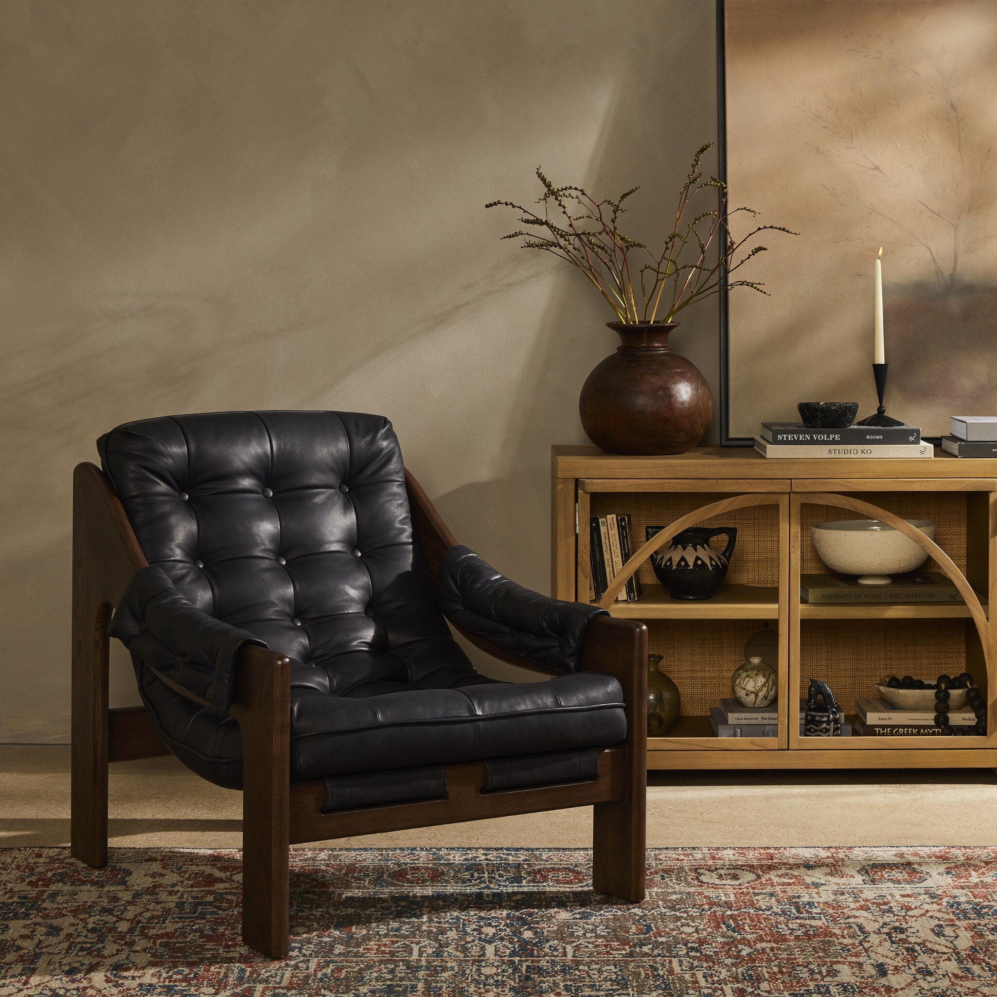 Black leather armchair in a room with a wooden shelf and decorative items.