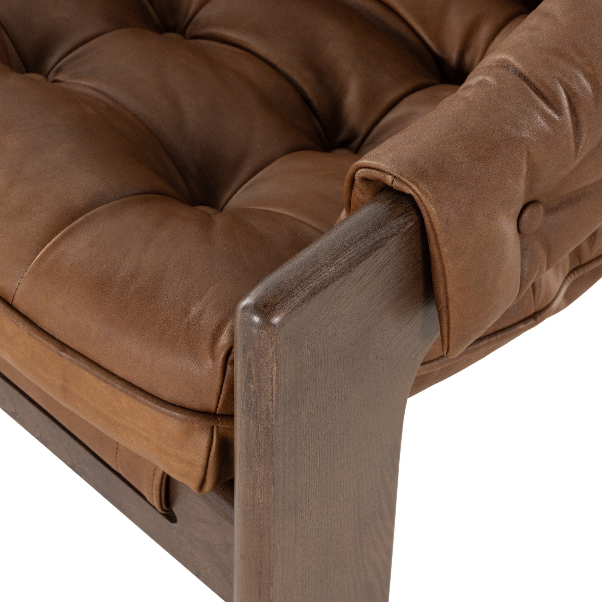Close-up of a brown leather armchair with tufted cushions on a white background