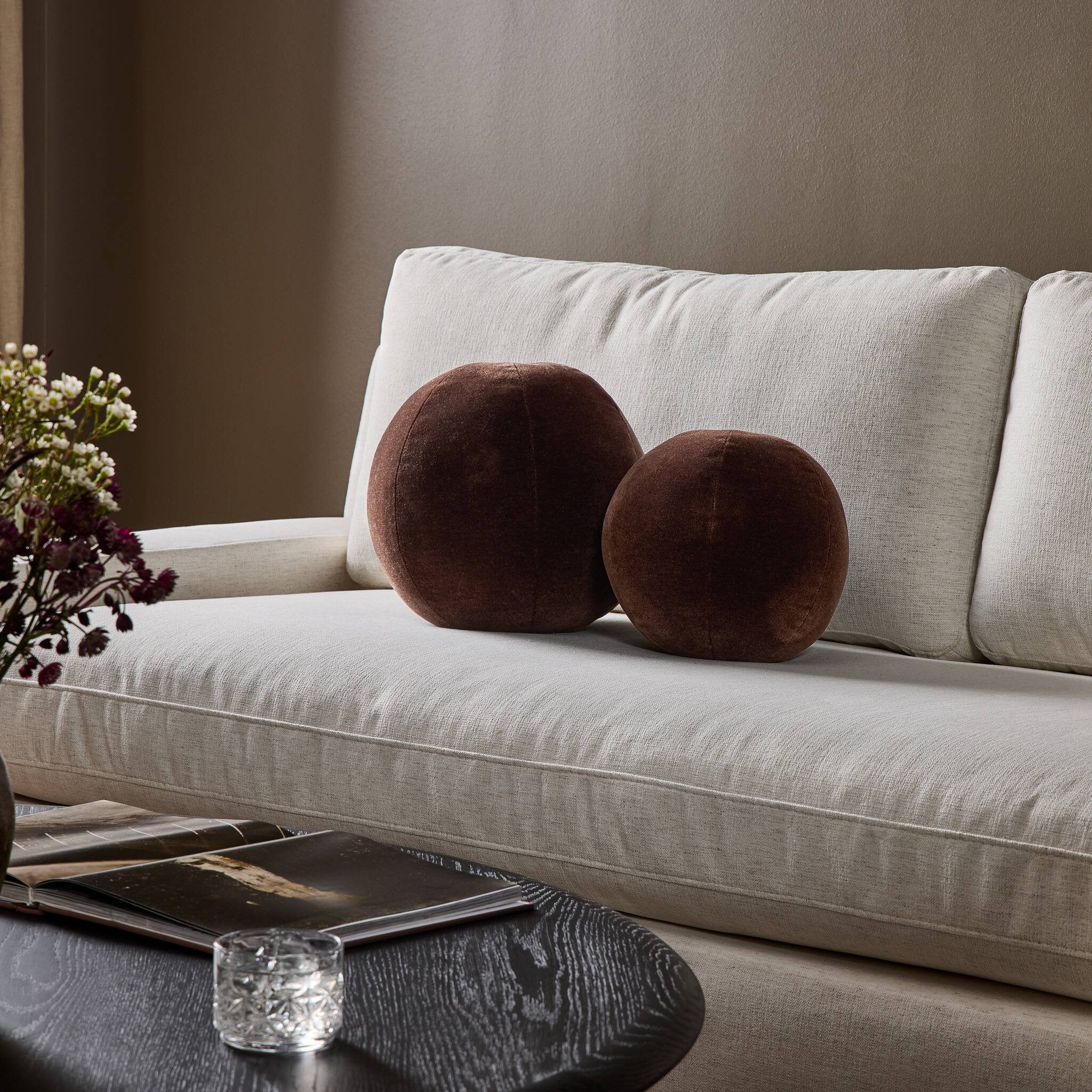 Beige sofa with brown round cushions in a living room setting.
