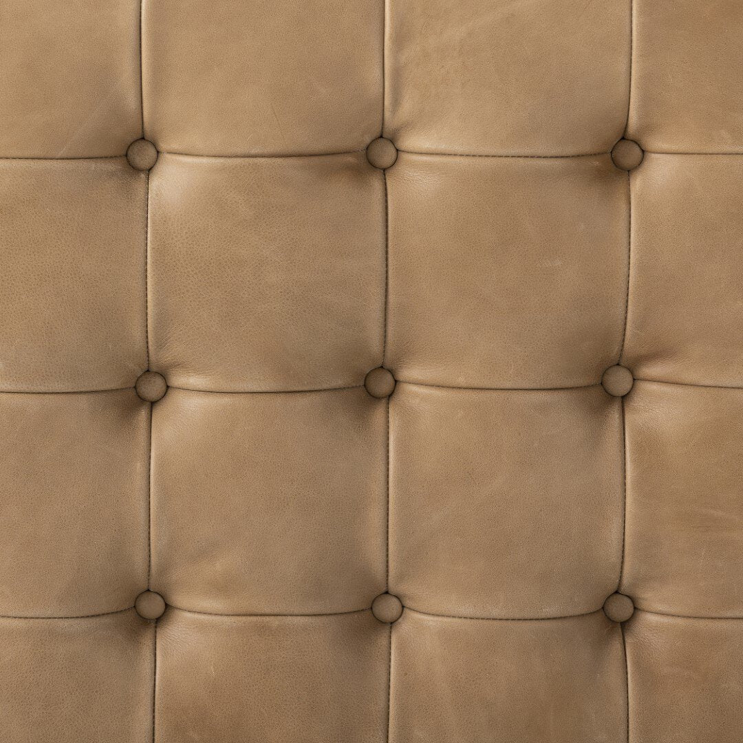 Close-up of a brown leather headboard with button tufting.