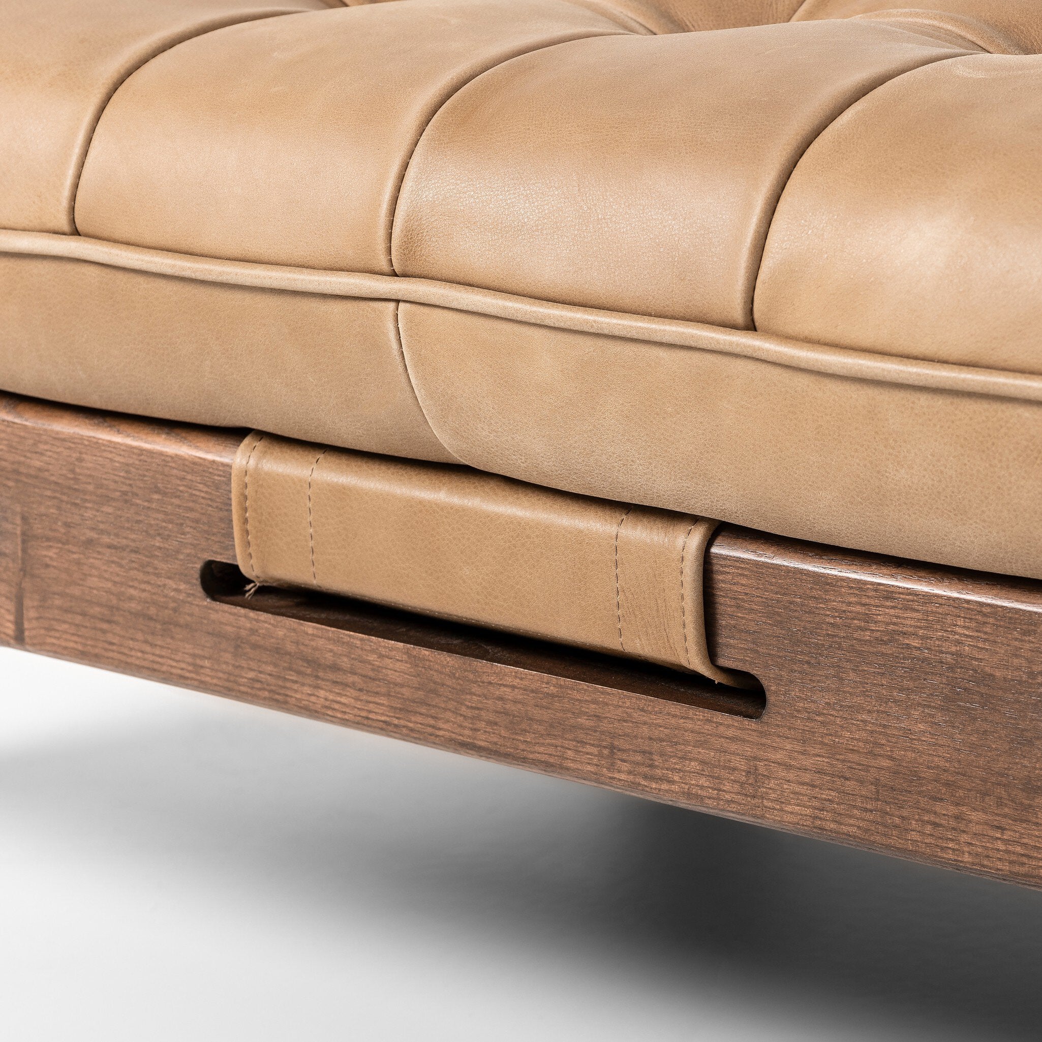 Close-up of a beige leather sofa with wooden armrests on a white background