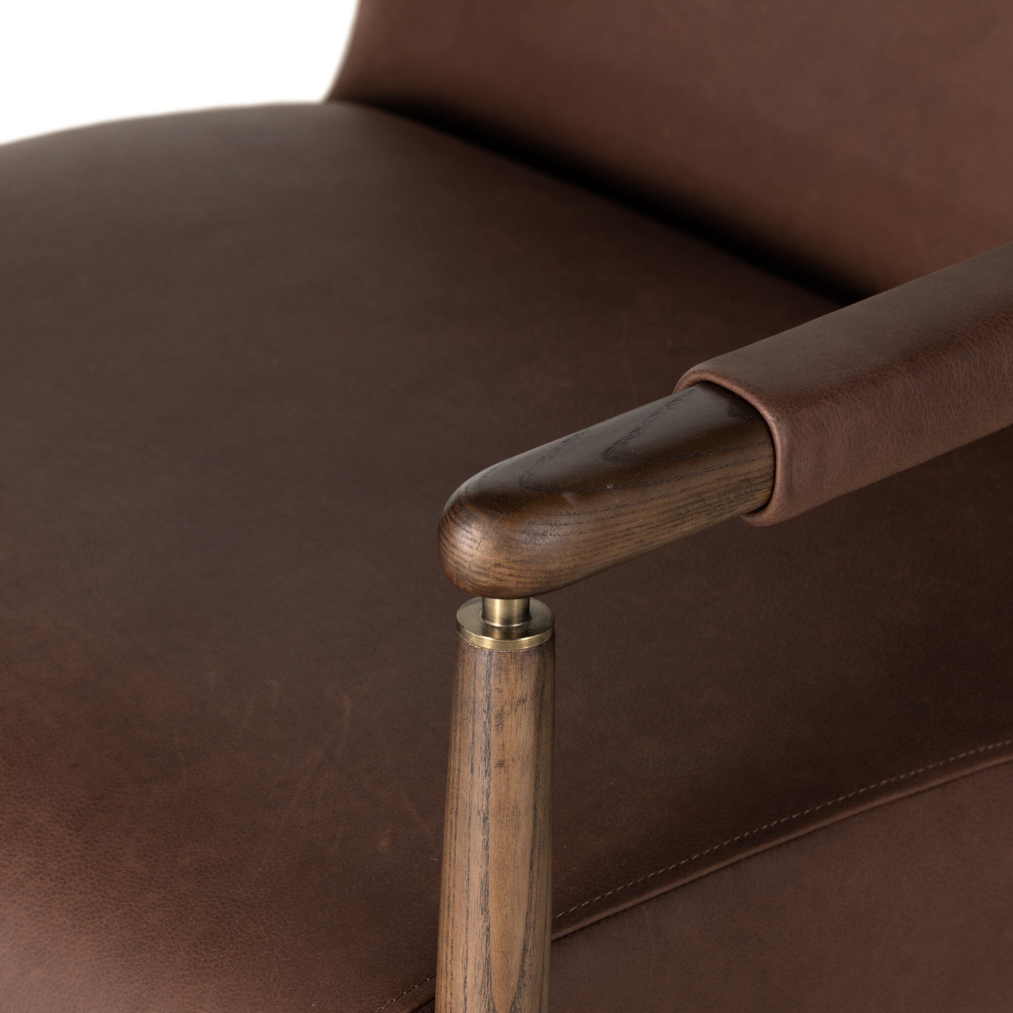 Close-up of a brown leather armchair with wooden armrests.