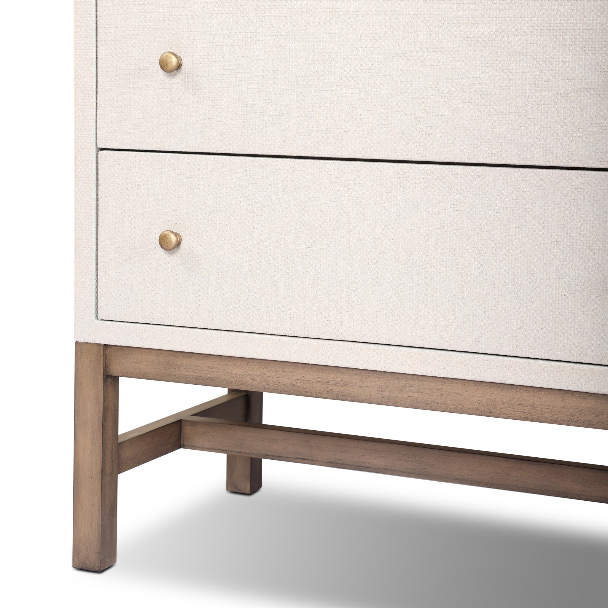 Close-up of a piece of off-white dresser with white drawers and wooden legs on a white background