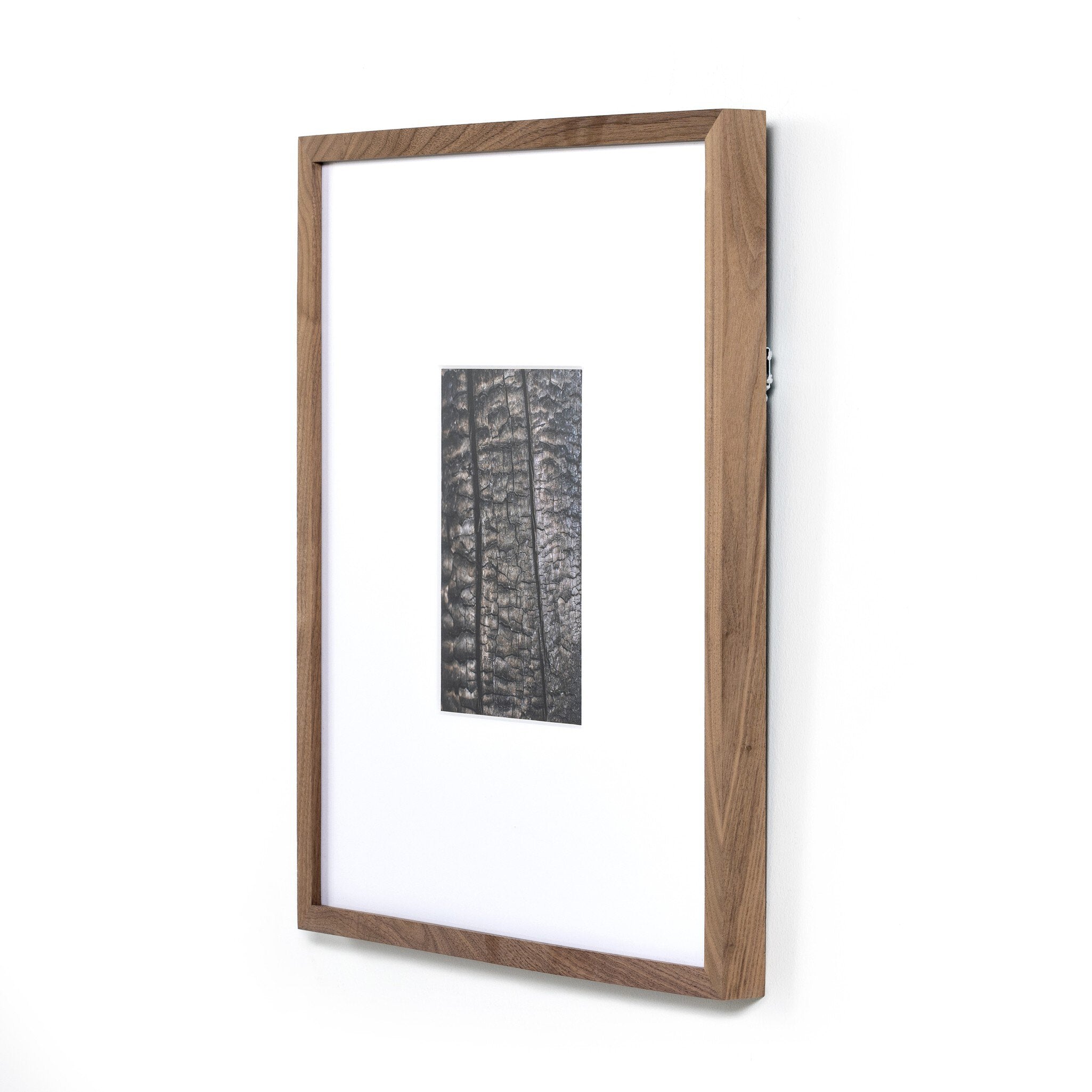 Wooden picture frame with a white mat and black and white artwork inside on a white background