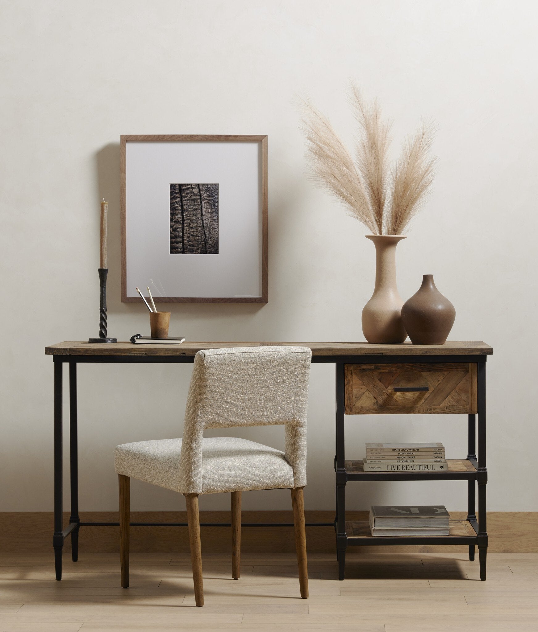 Wooden desk with chair, framed artwork, and decorative vases in a room setting.