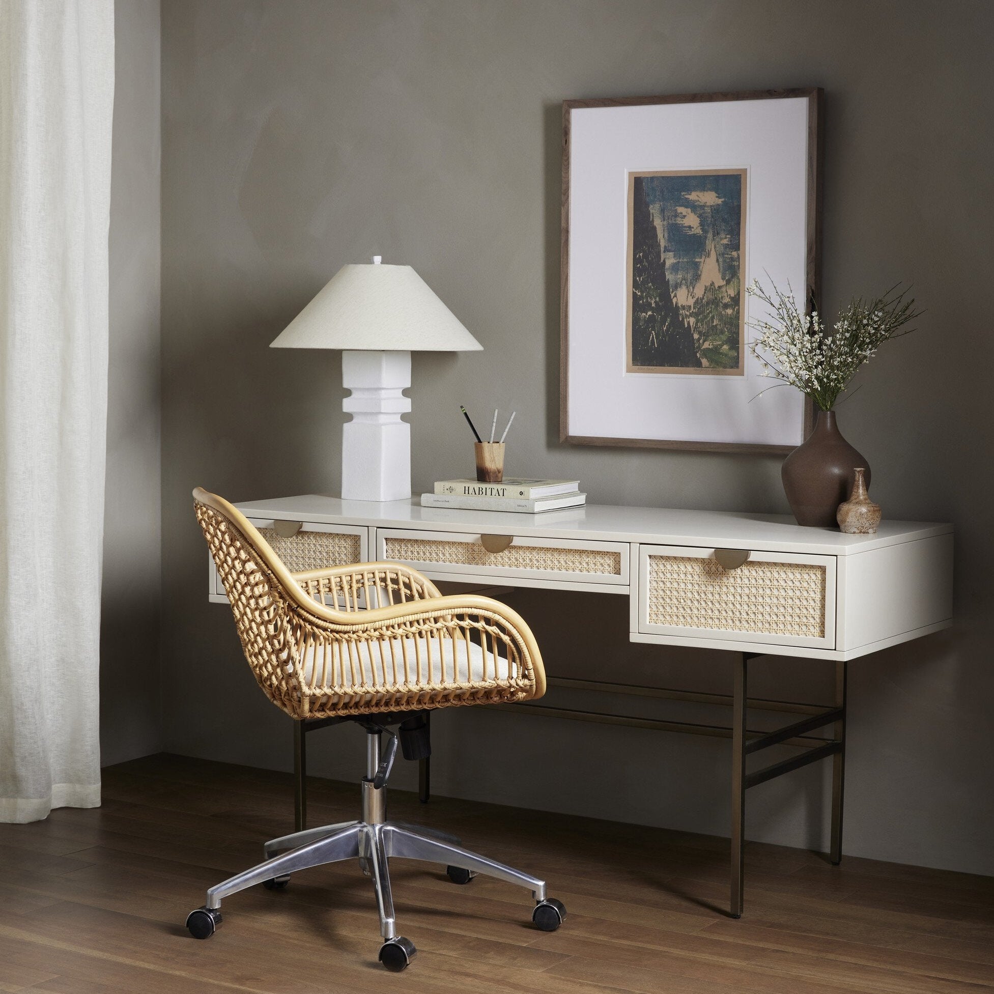 Modern home office with a desk, chair, lamp, and decorative items.