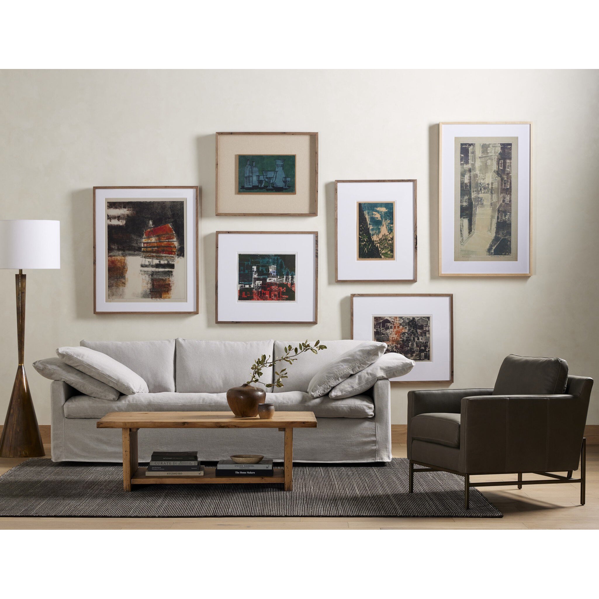 Living room with a gray sofa, armchair, and coffee table with framed pictures on the wall.
