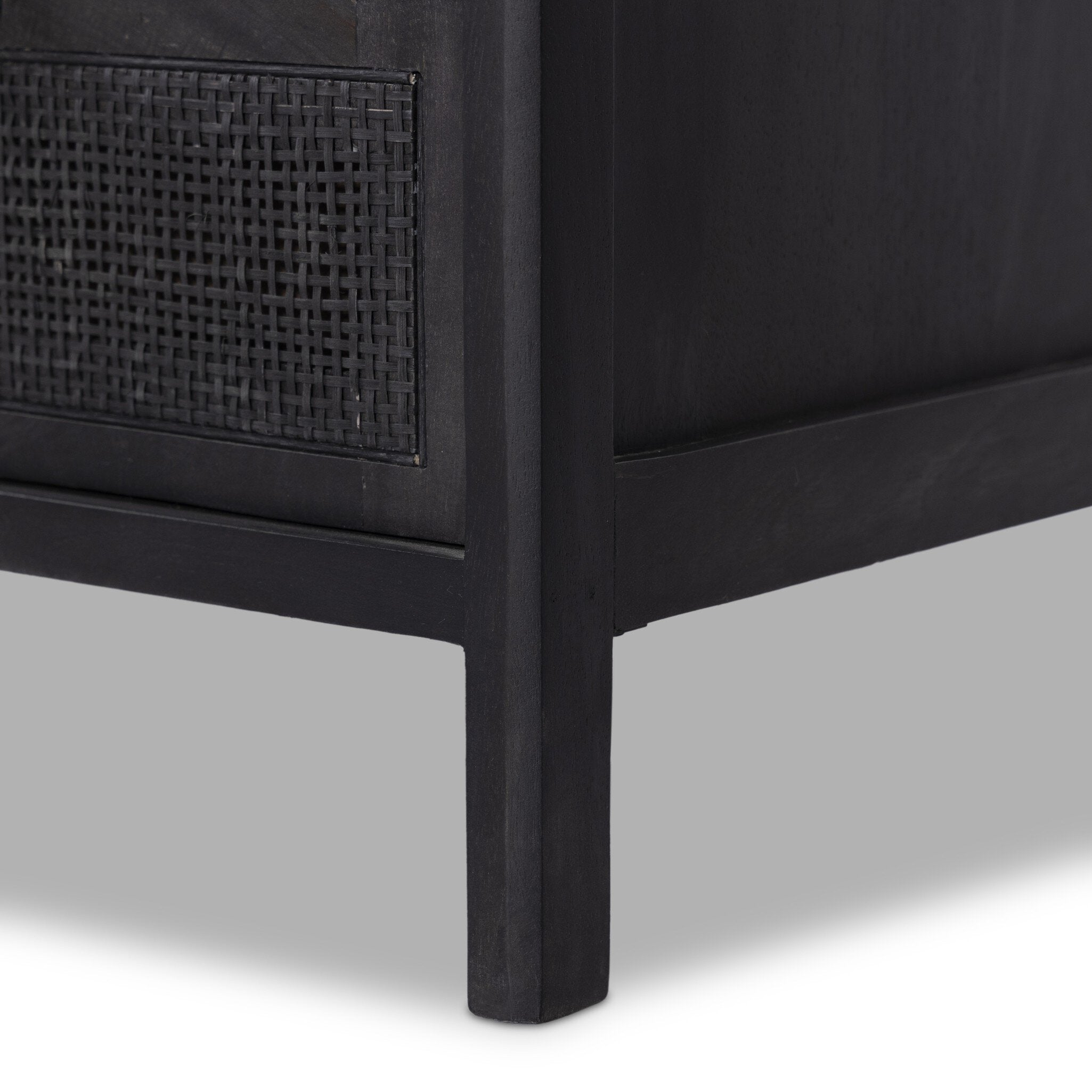 Black wooden furniture leg with woven pattern on a gray background