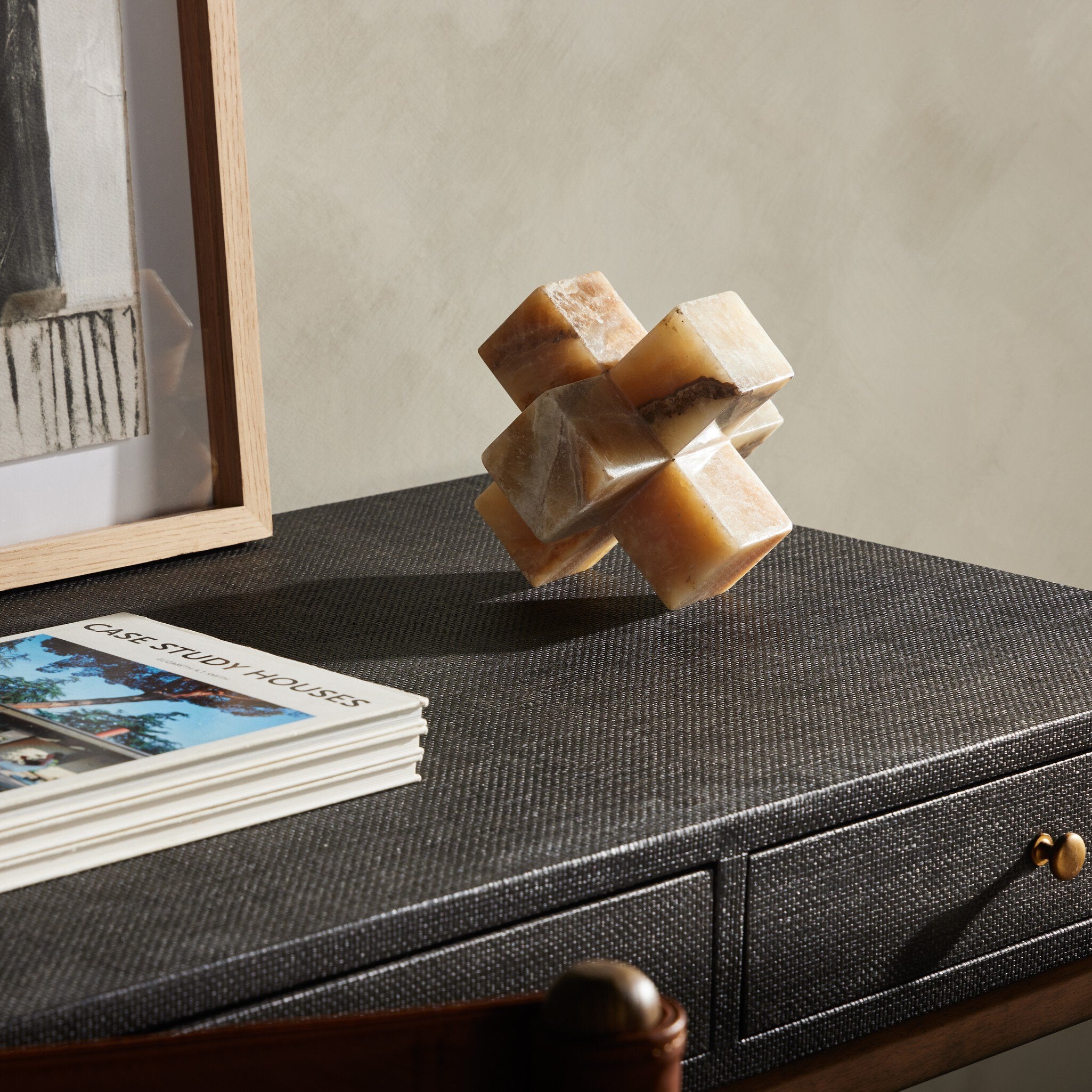Onyx jack sculpture on a textured surface with a book and framed picture in the background