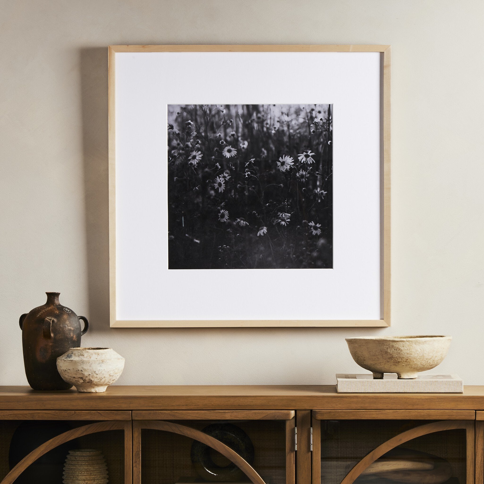 Framed black and white floral print on a wall above a wooden console table with decorative items.