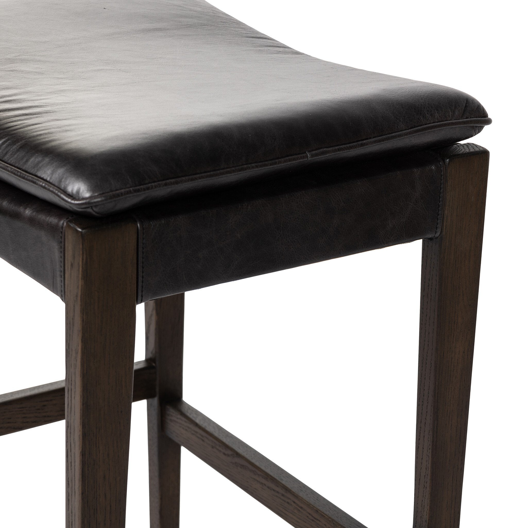 Wooden stool with black leather seat on a white background