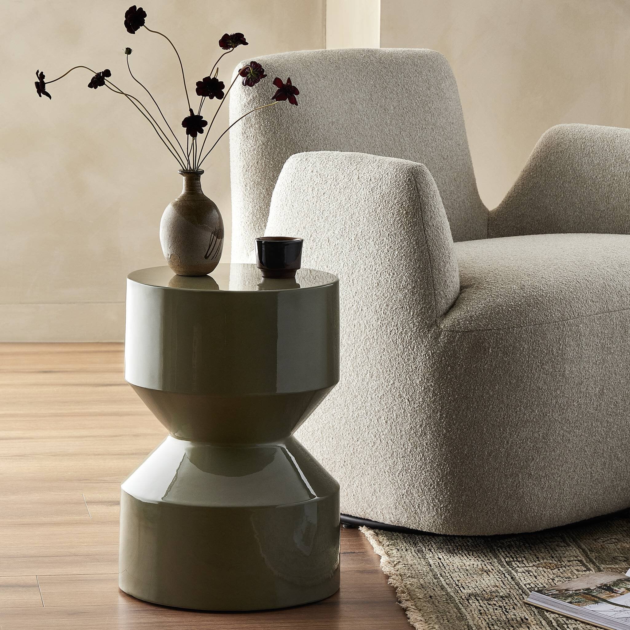 Gray armchair with a green side table and decorative items in a living room setting.